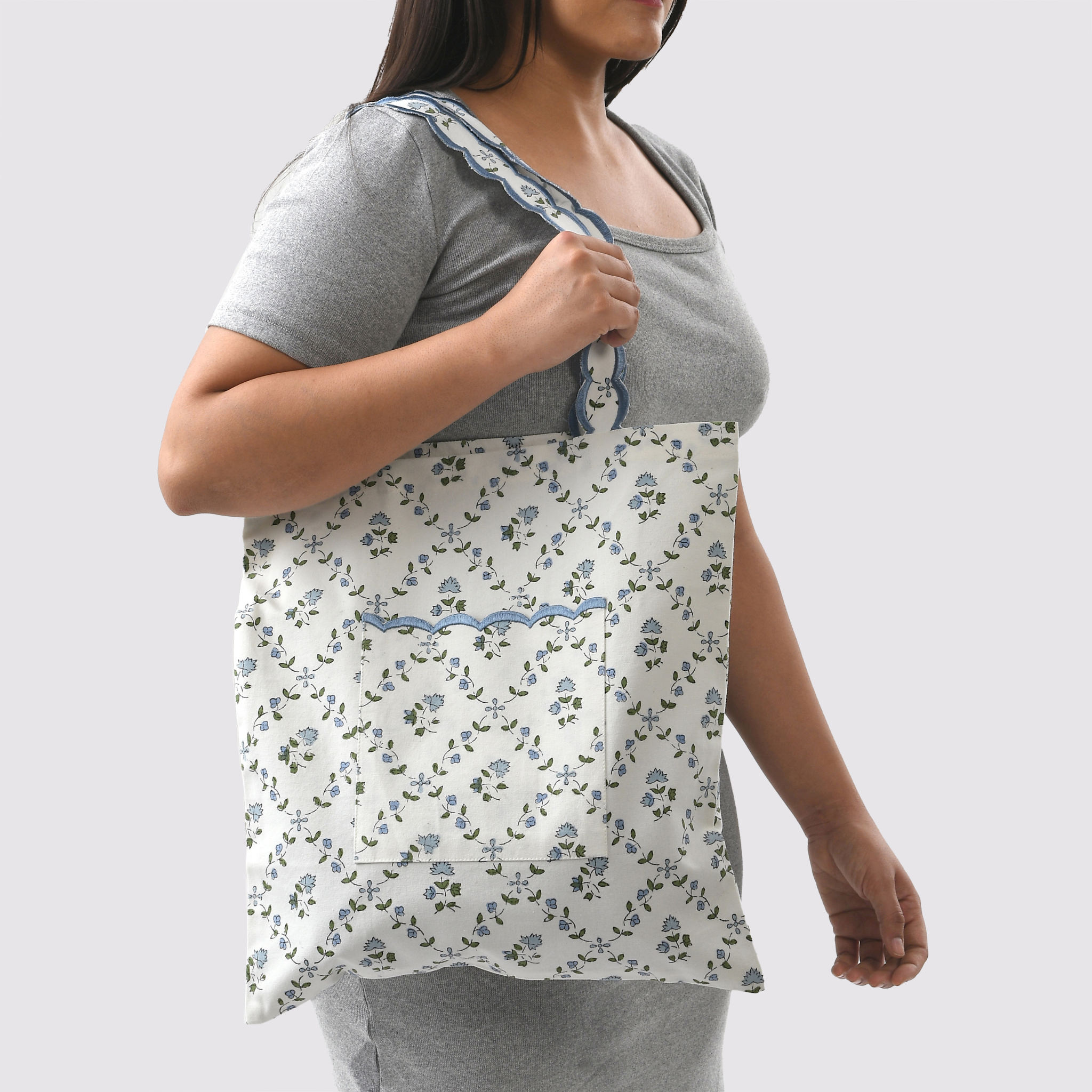 Woman wearing a gray t-shirt with a floral apron over it on a white background