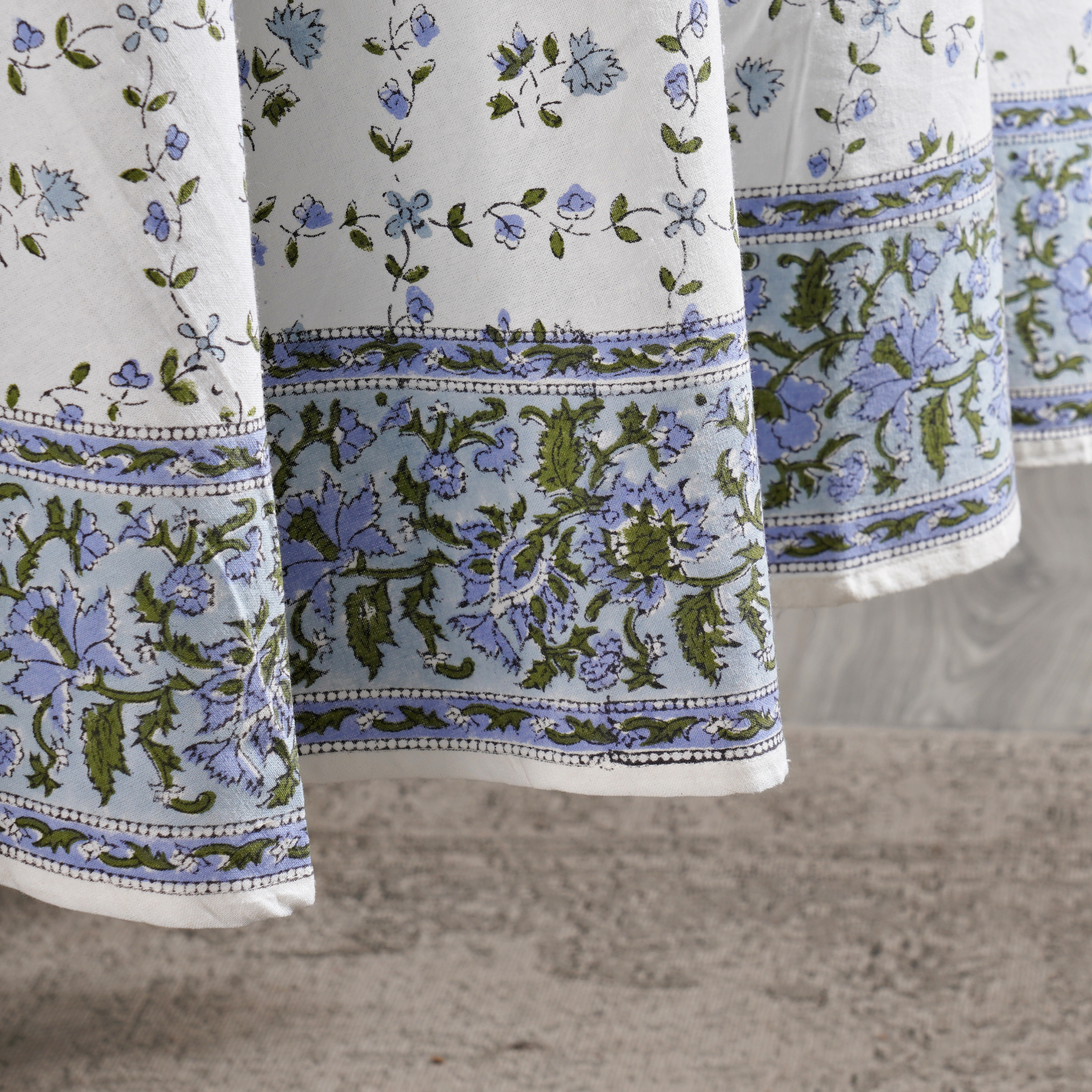 Close-up of floral-patterned fabric with blue and green designs on a neutral background