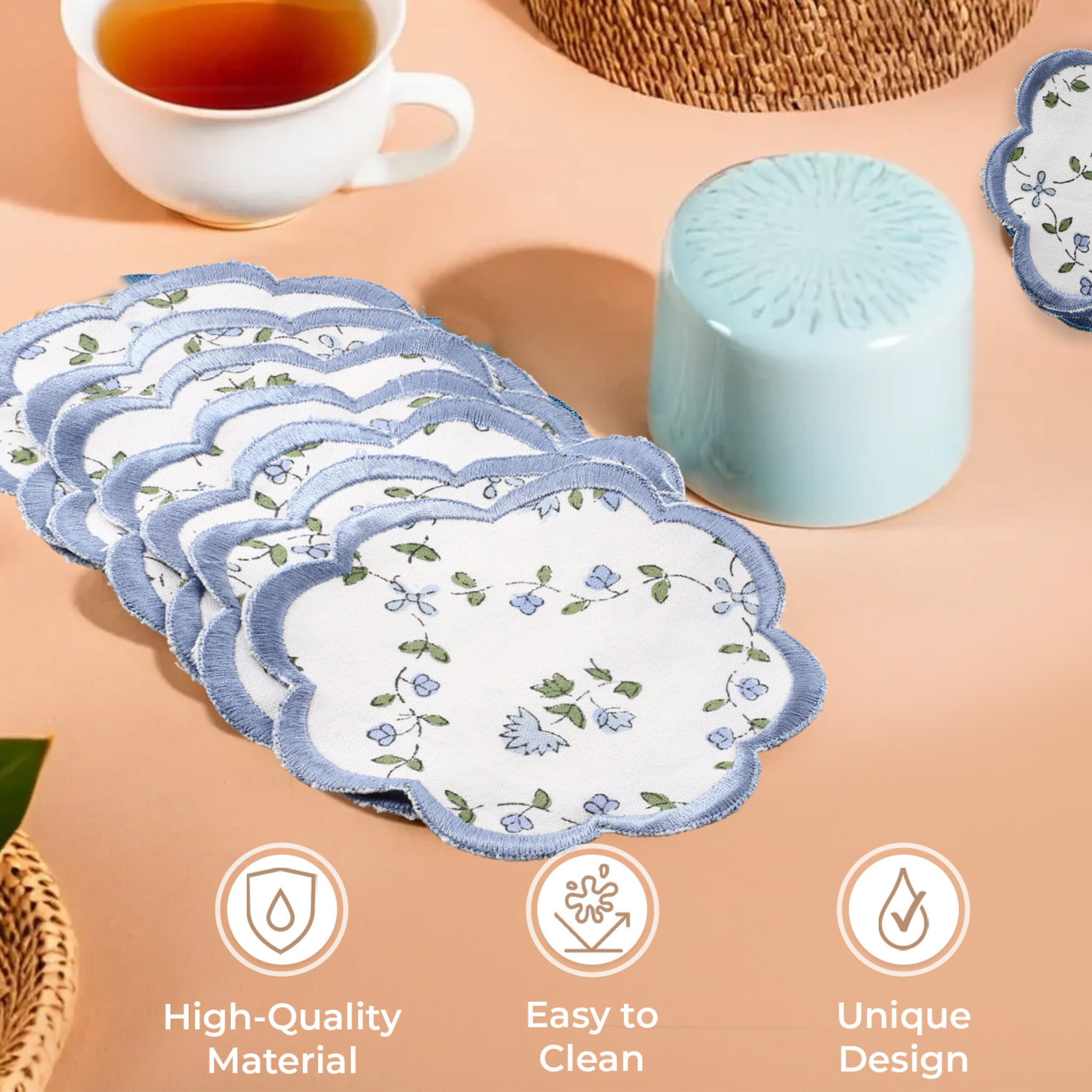 Set of floral coasters with a cup of tea and a candle on a beige surface.