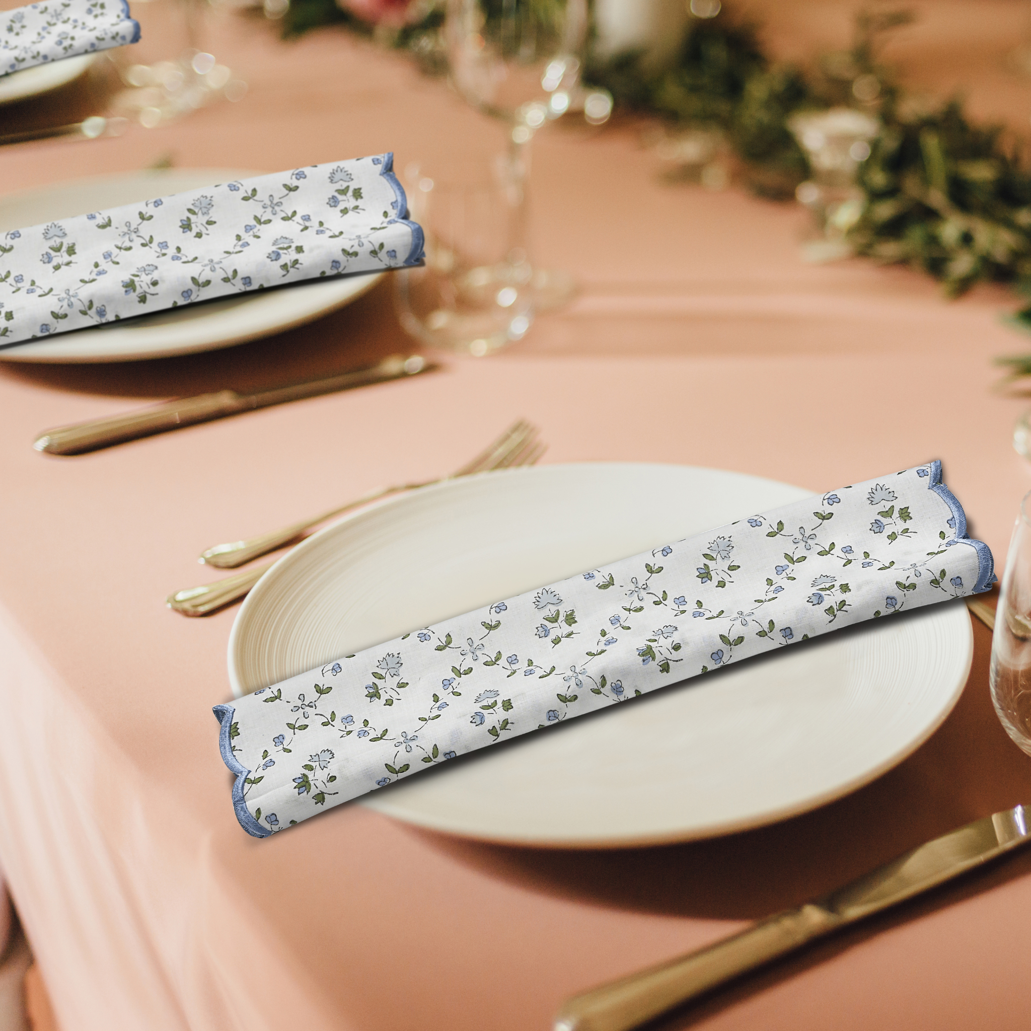 Table setting with floral-patterned napkins on a pink tablecloth.