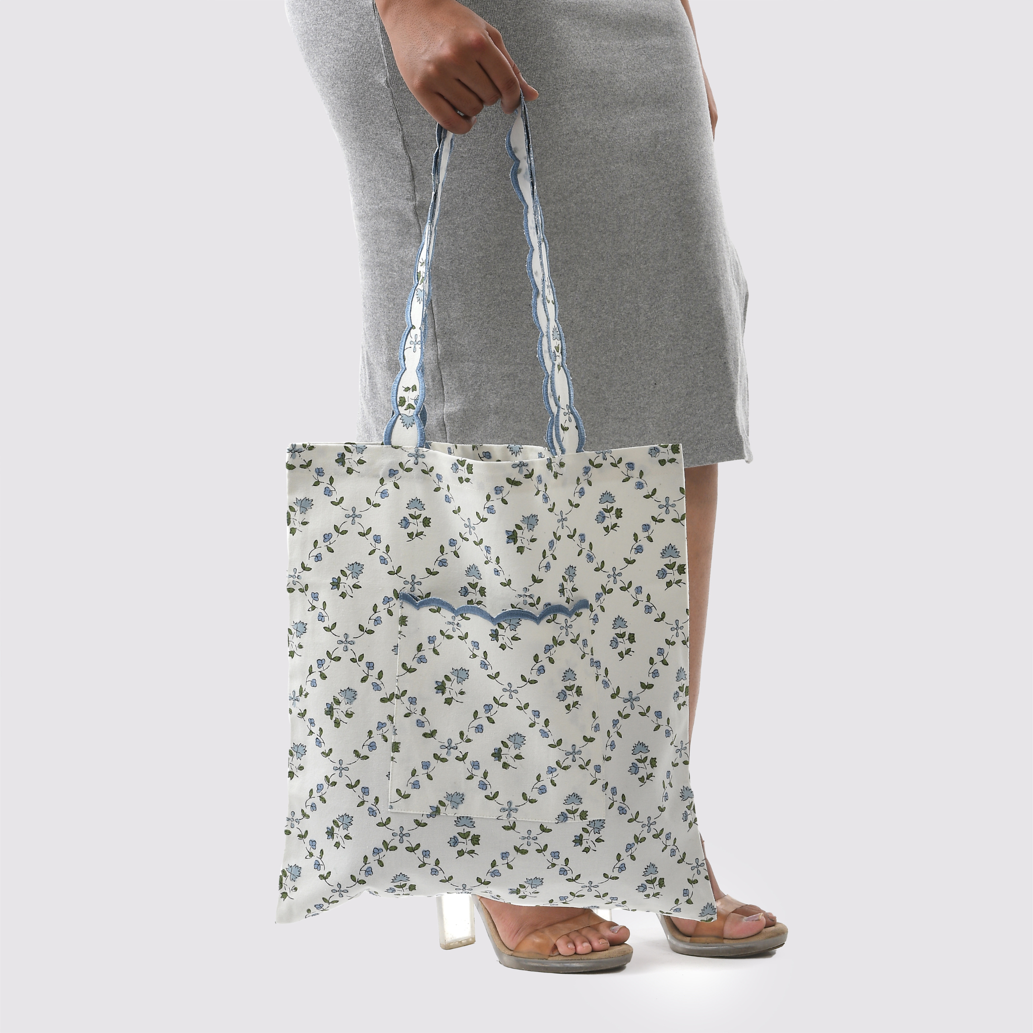Person holding a floral-patterned tote bag against a plain background