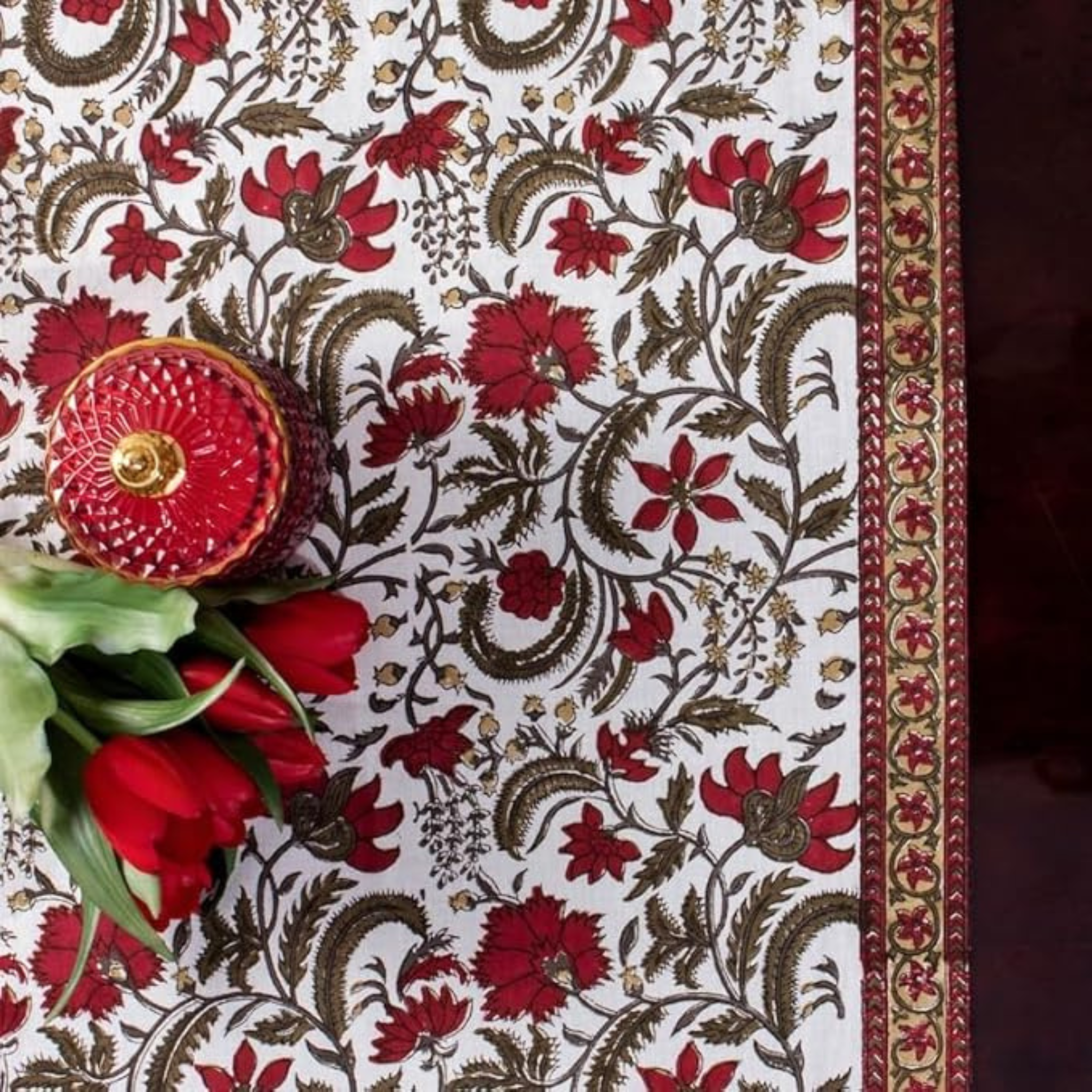 Decorative fabric with floral patterns and a red decorative item on a white background