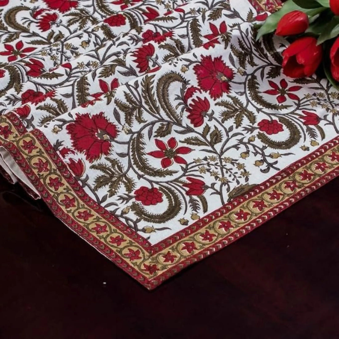 Decorative tablecloth with floral pattern and red flowers on a dark surface