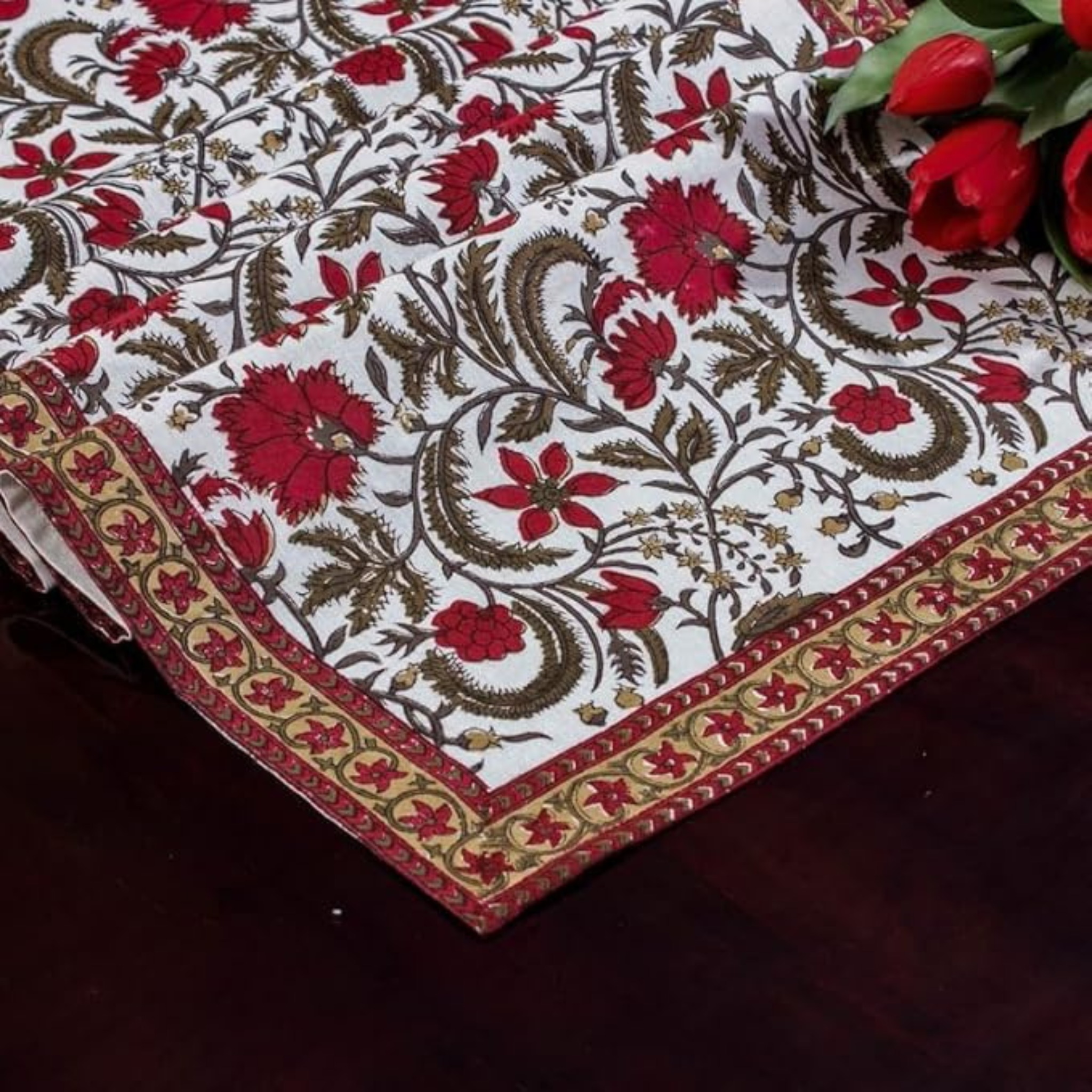 Decorative tablecloth with floral pattern and red flowers on a dark surface