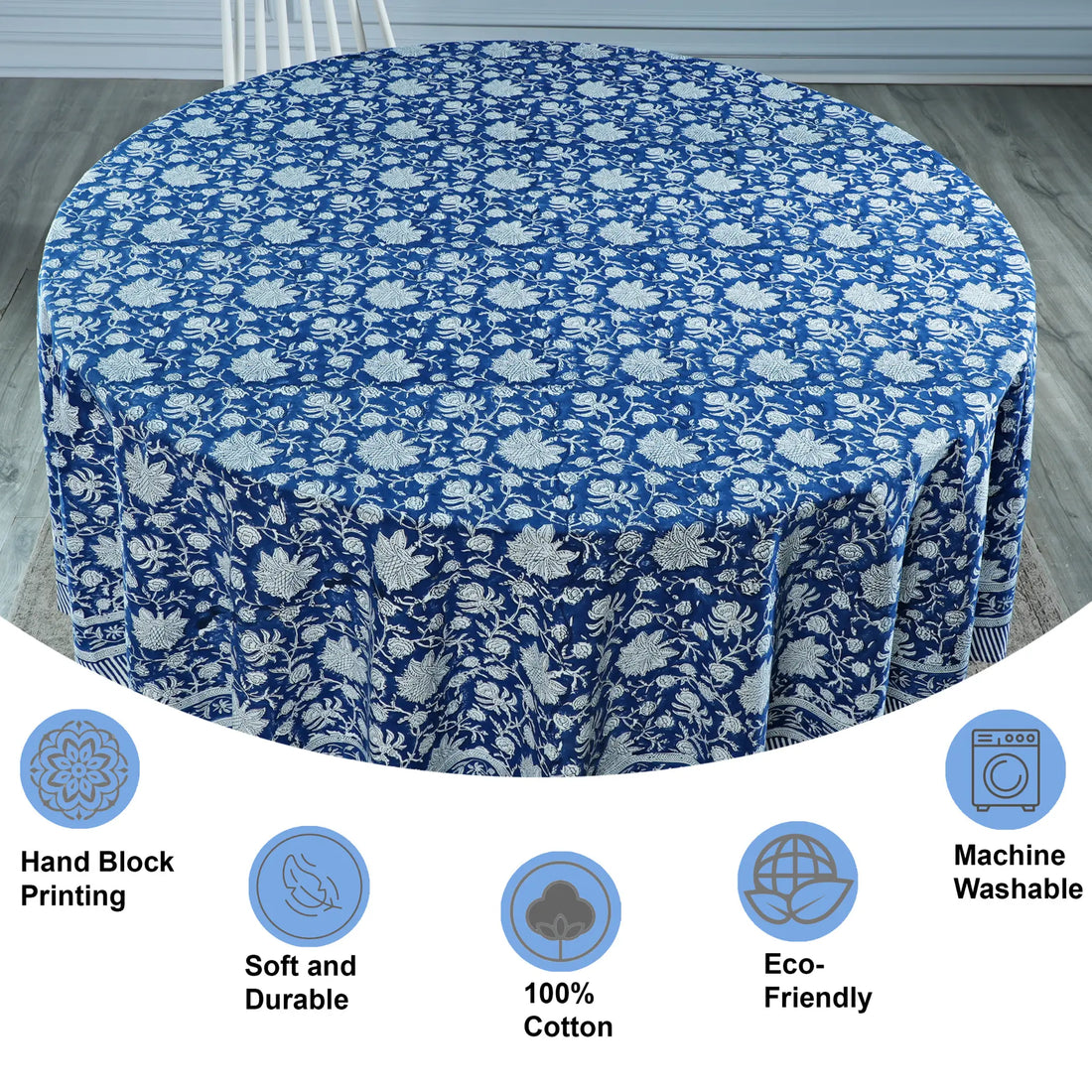 Round table covered with a blue floral patterned tablecloth on a wooden floor.