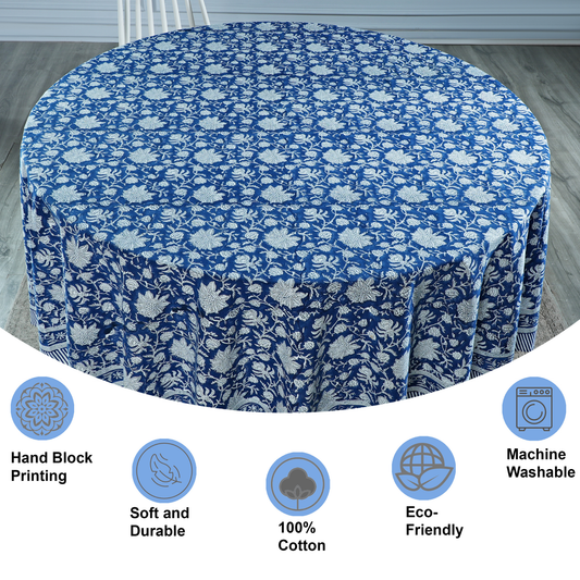 Round table covered with a blue floral patterned tablecloth on a wooden floor.