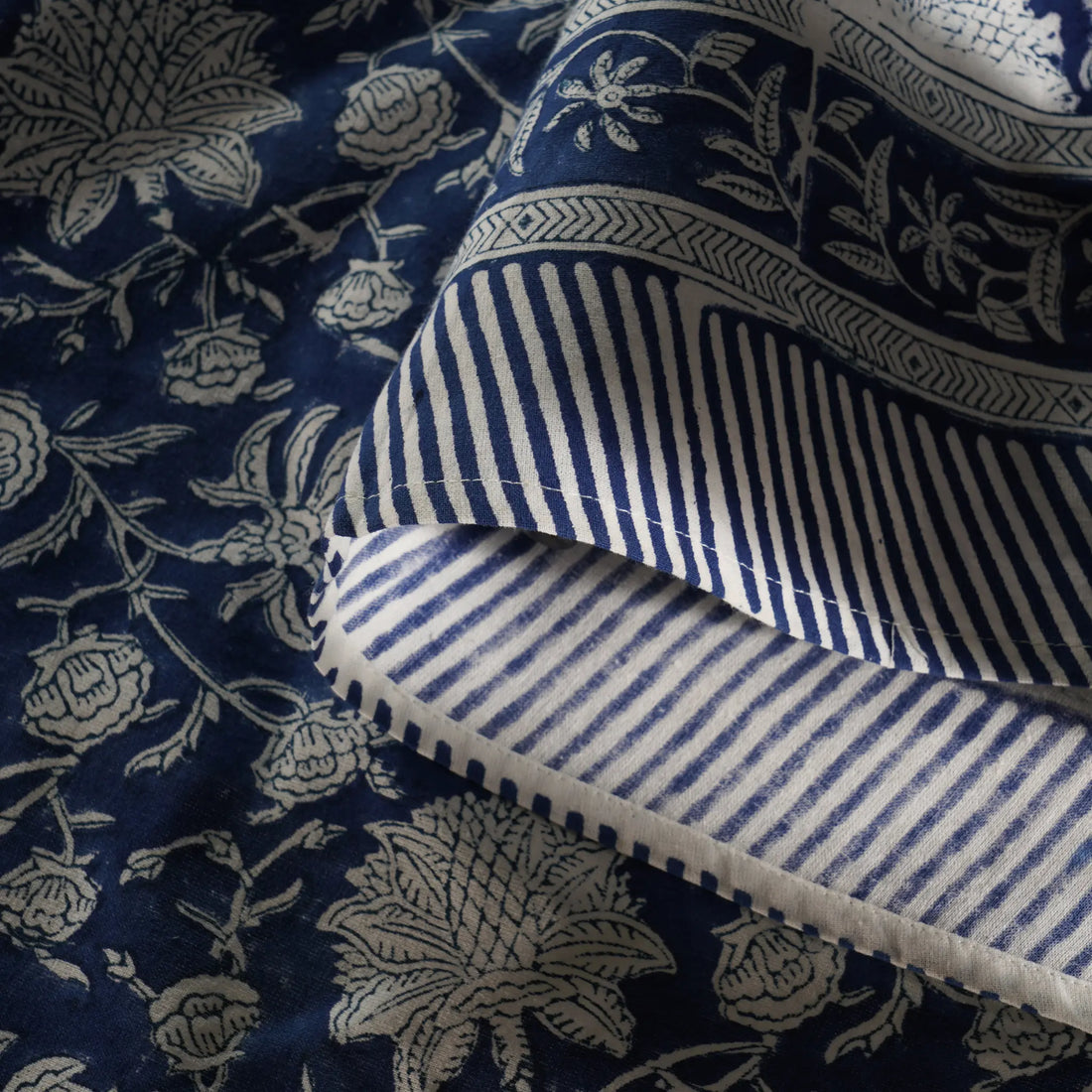 Close-up of blue and white patterned fabric with floral and striped designs.