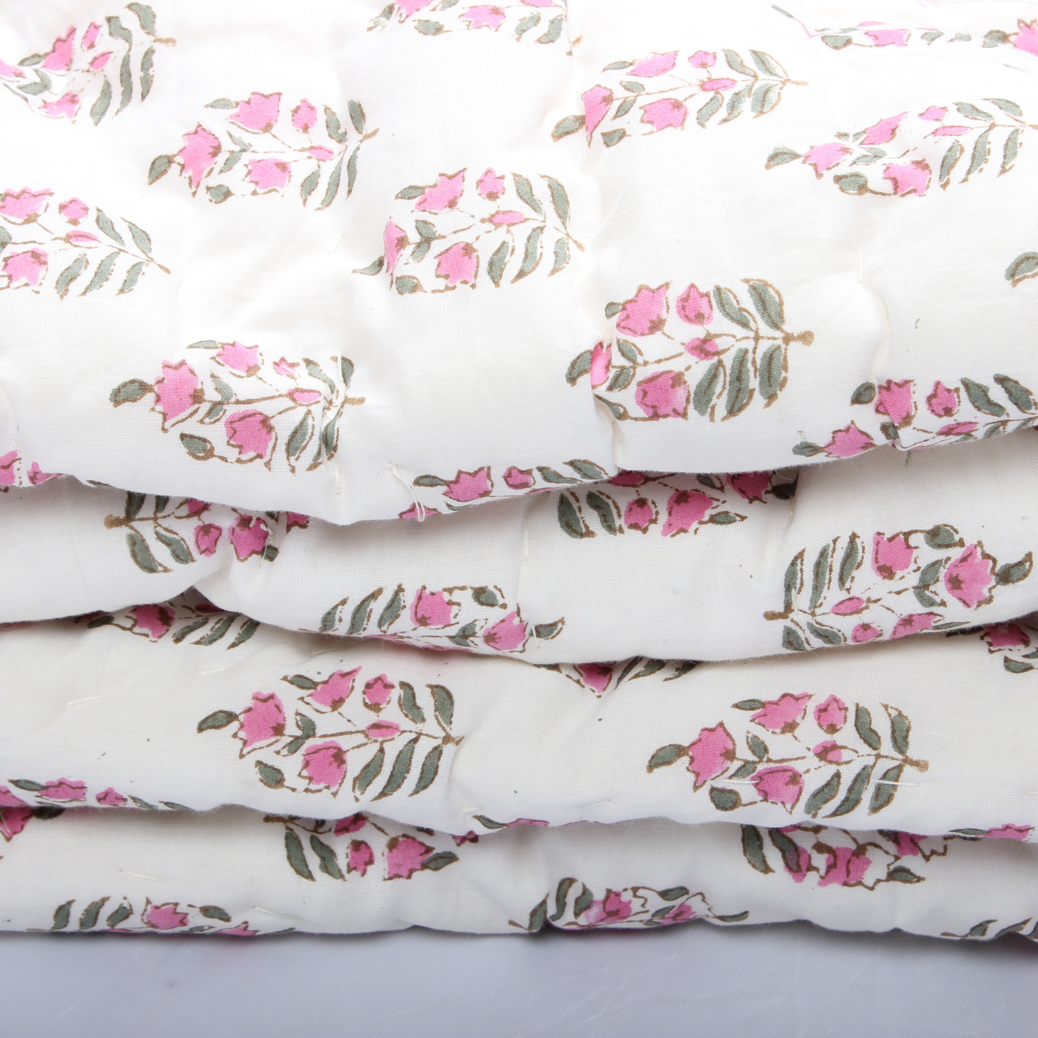 Stack of white fabric with pink floral patterns on a light gray background