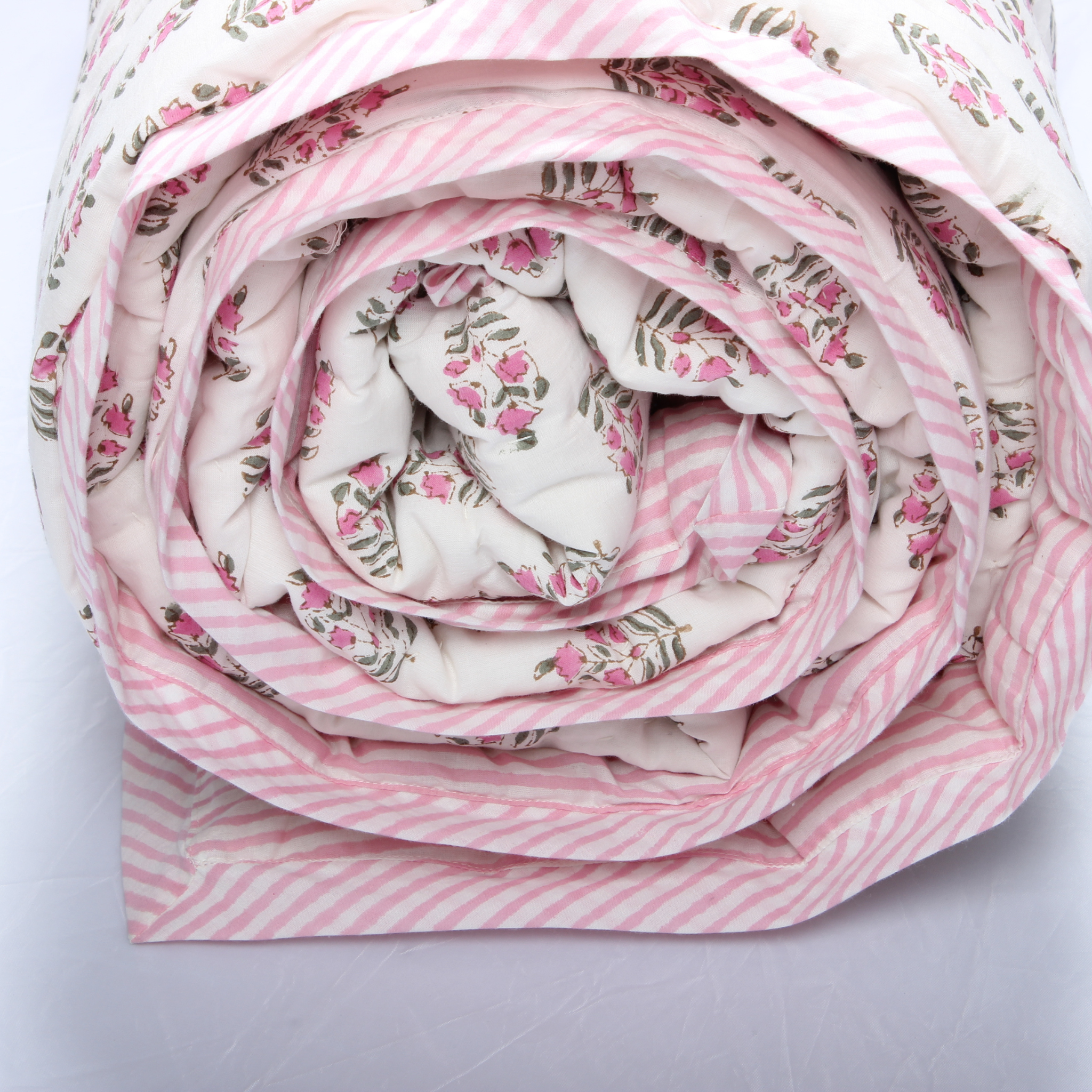 Rolled-up fabric with pink floral and striped patterns on a light gray background