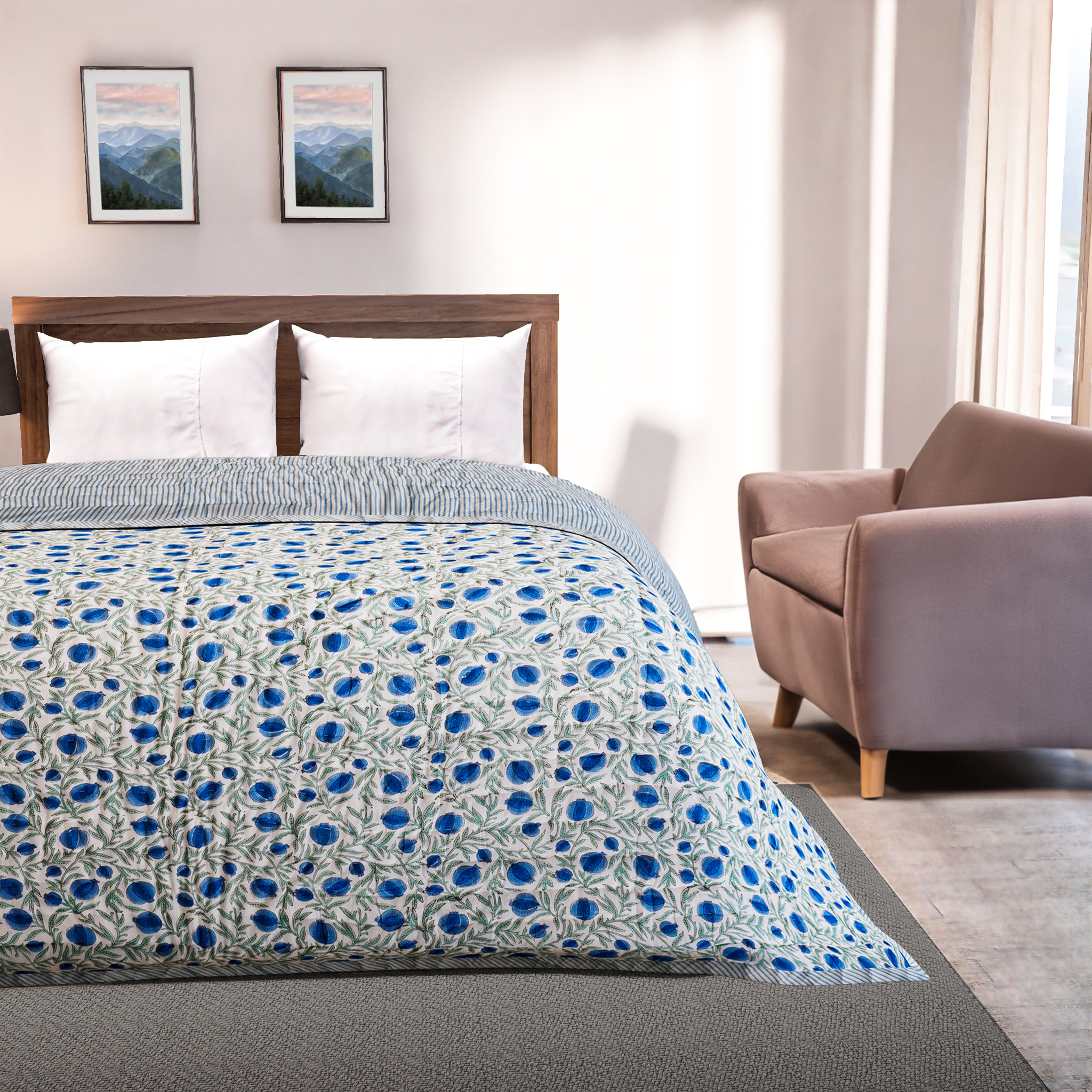Bedroom with a bed covered in a blue and white patterned comforter, wooden headboard, and armchair.