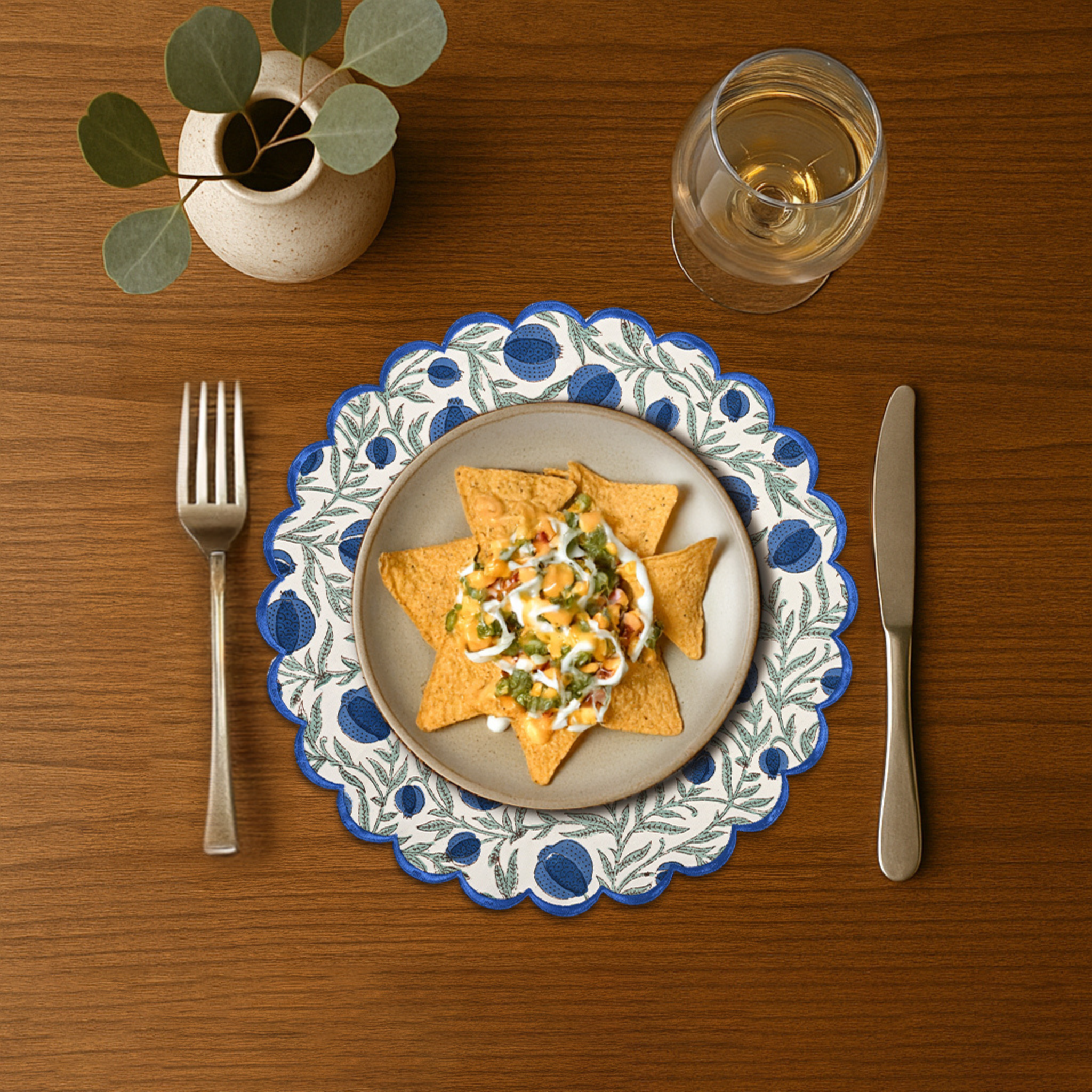 Dinner setting with a plate of food, fork, knife, and glass on a wooden table.