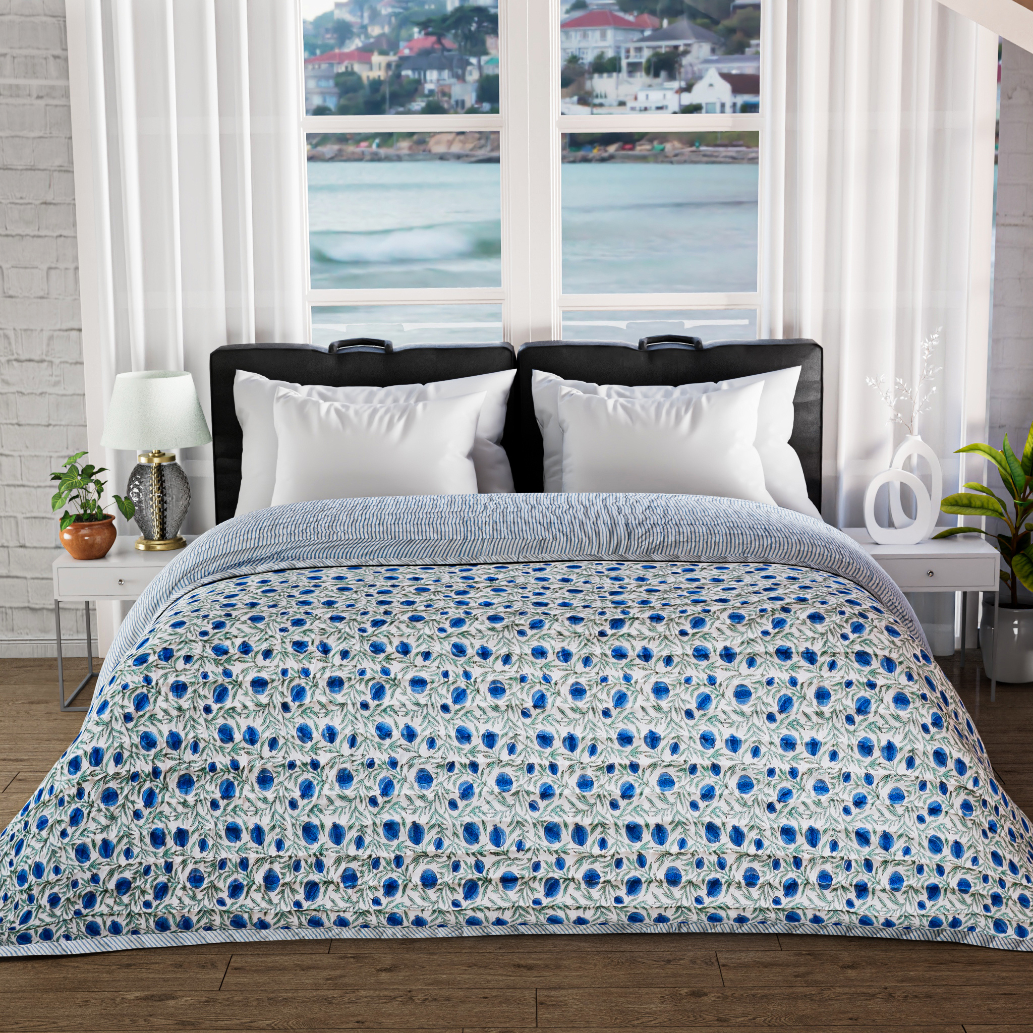 Bed with blue and white patterned comforter in a room with large windows showing a waterfront view.