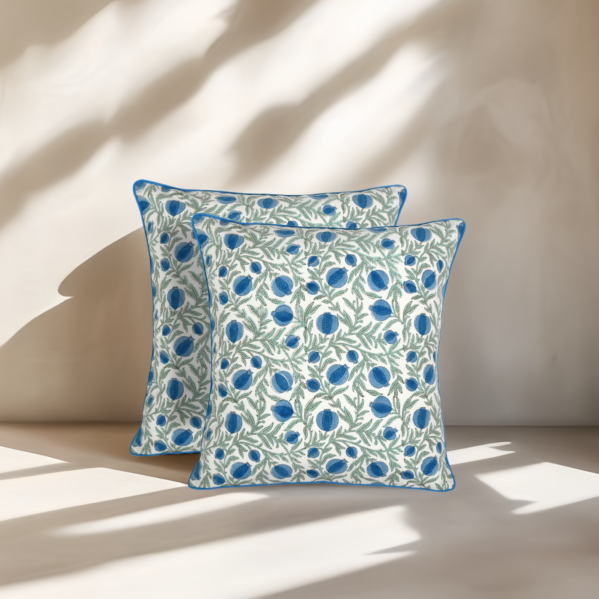 Two decorative pillows with blue floral pattern on a beige background