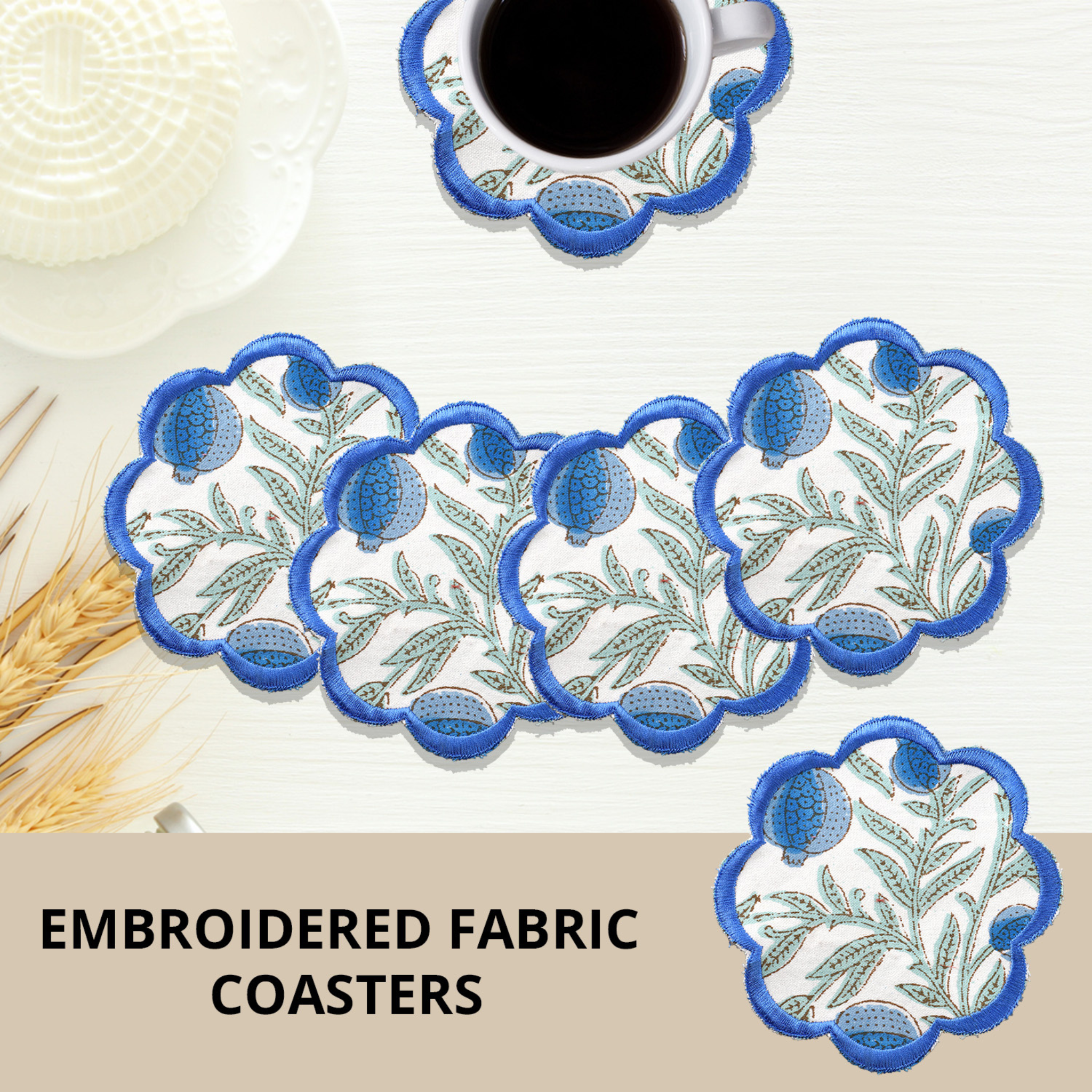 Set of embroidered fabric coasters with blue and green design on a white surface.