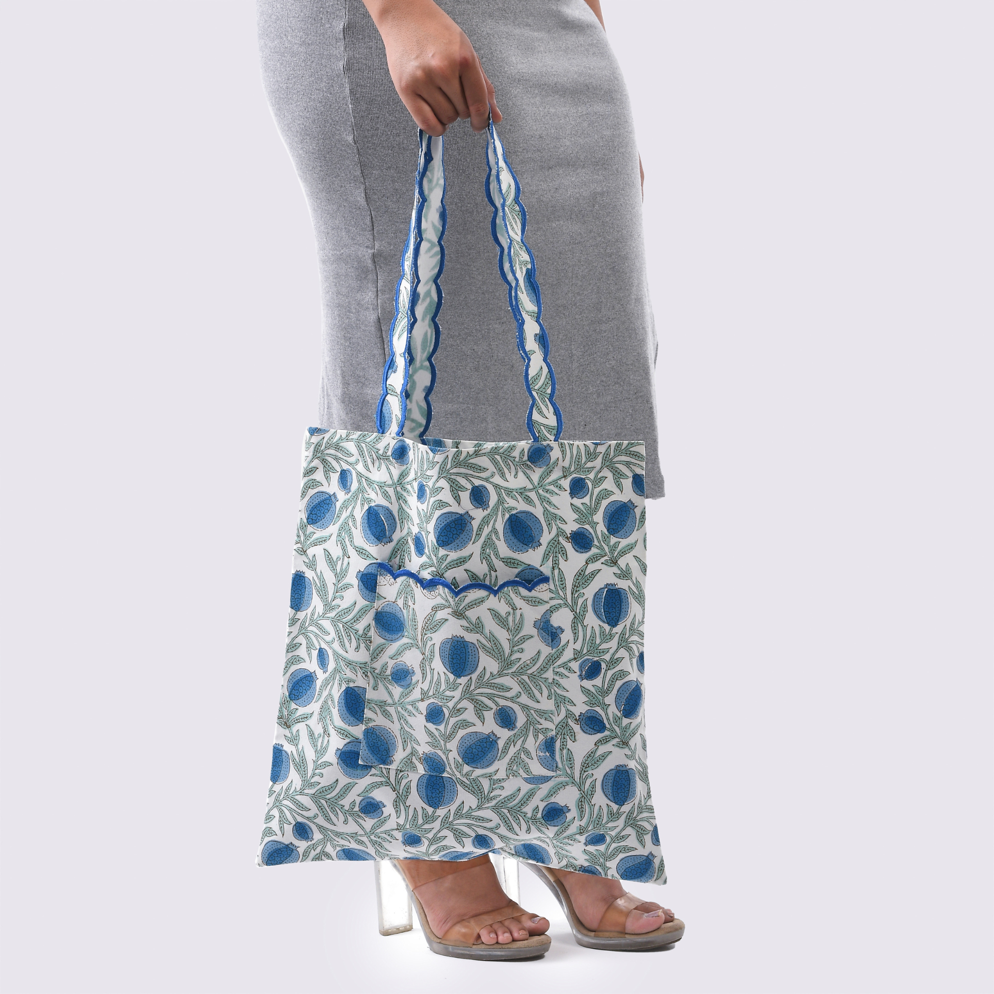 Person holding a floral-patterned tote bag against a plain background