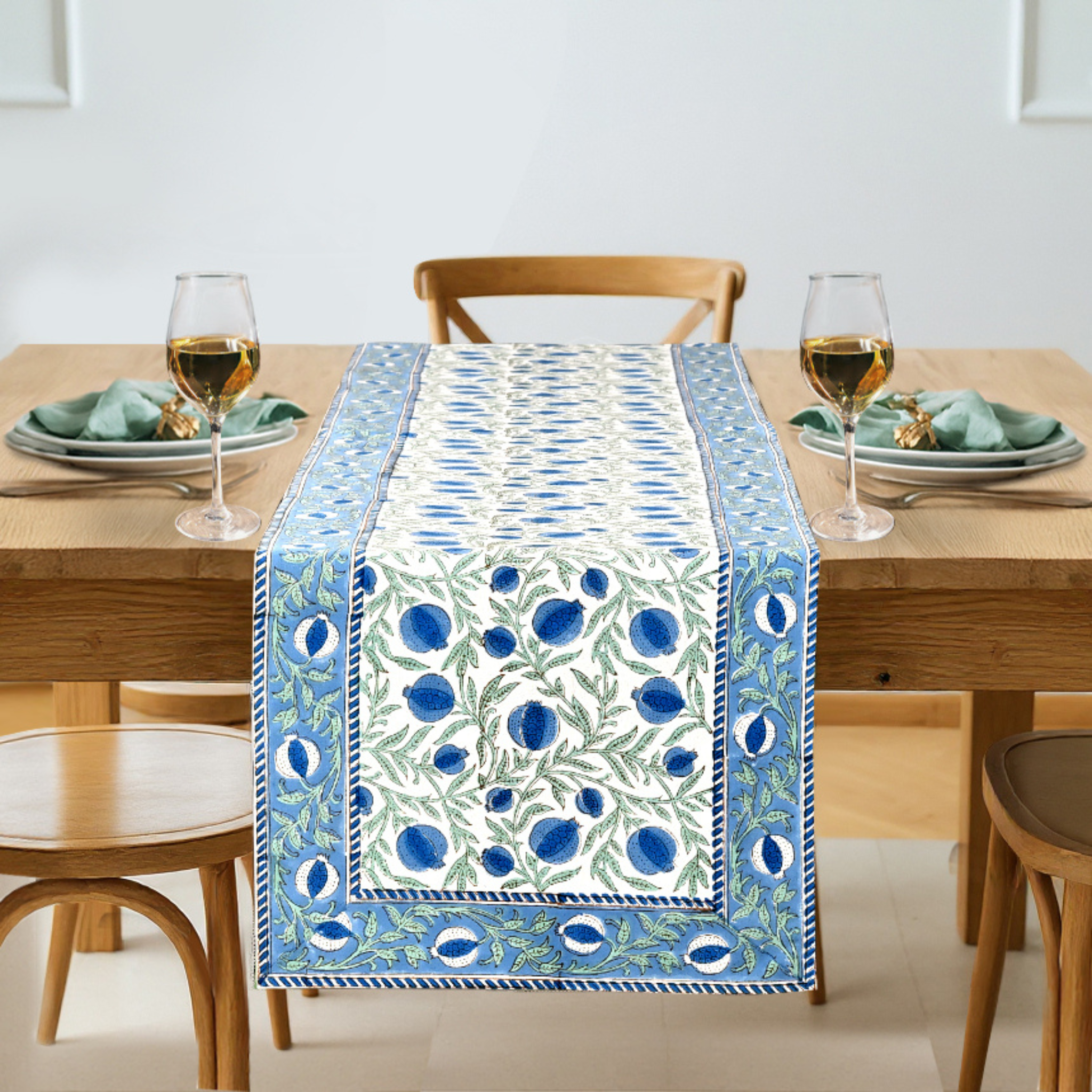 Dining table set with a decorative blue and white table runner, glasses, and plates.