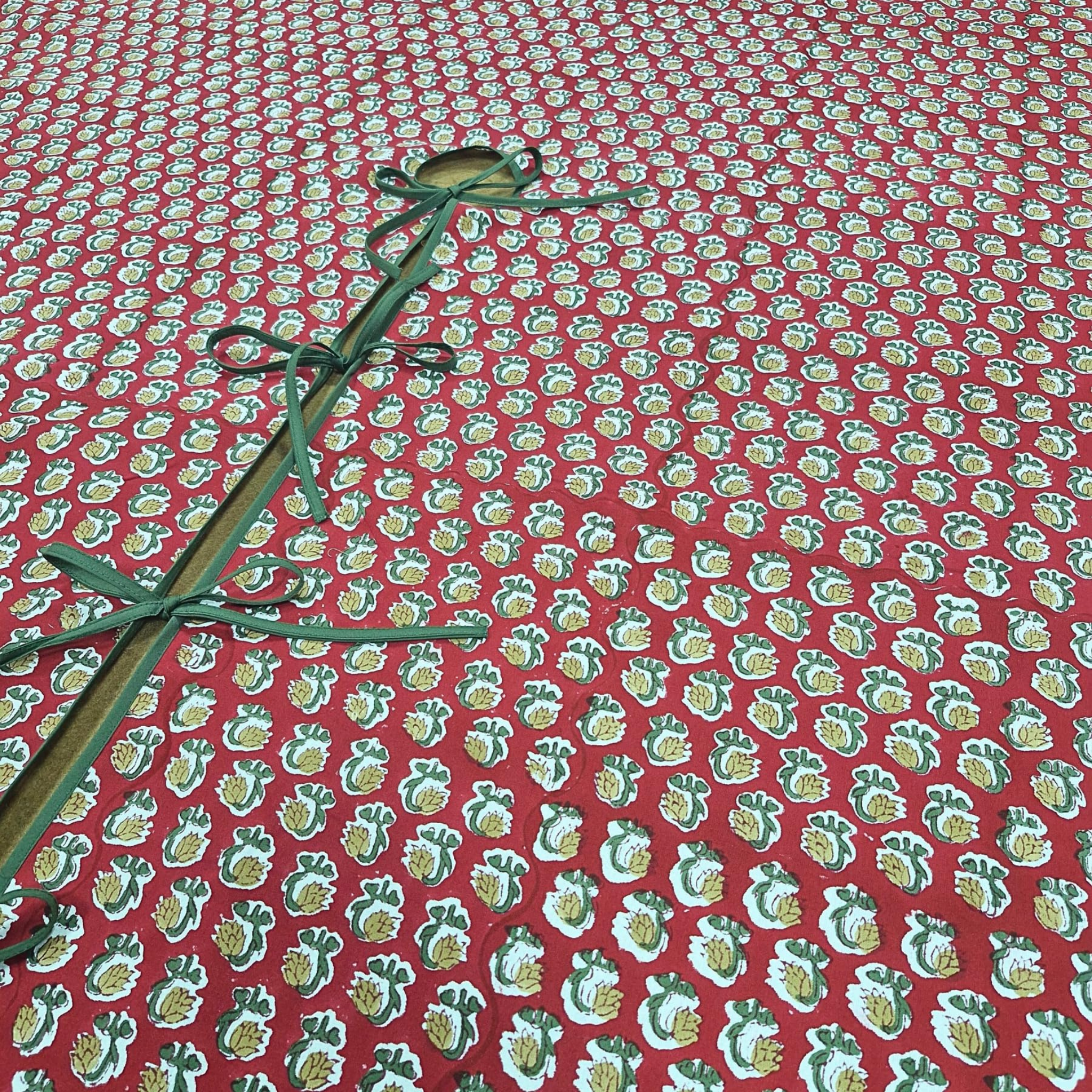 Red fabric with green floral pattern and green ribbon on a red background