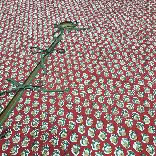 Red fabric with green floral pattern and green ribbon on a red background