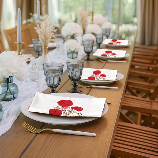 Dining table set with floral napkins, glasses, and cutlery in a bright room.