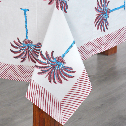 Decorative tablecloth with red and white palm tree pattern on a plain background with striped border