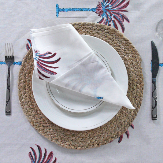Decorative tablecloth with red and white palm tree pattern on a plain background with striped border