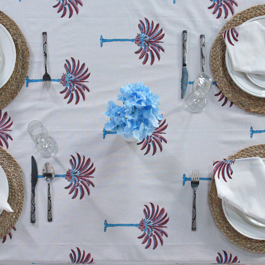 Decorative tablecloth with red and white palm tree pattern on a plain background with striped border