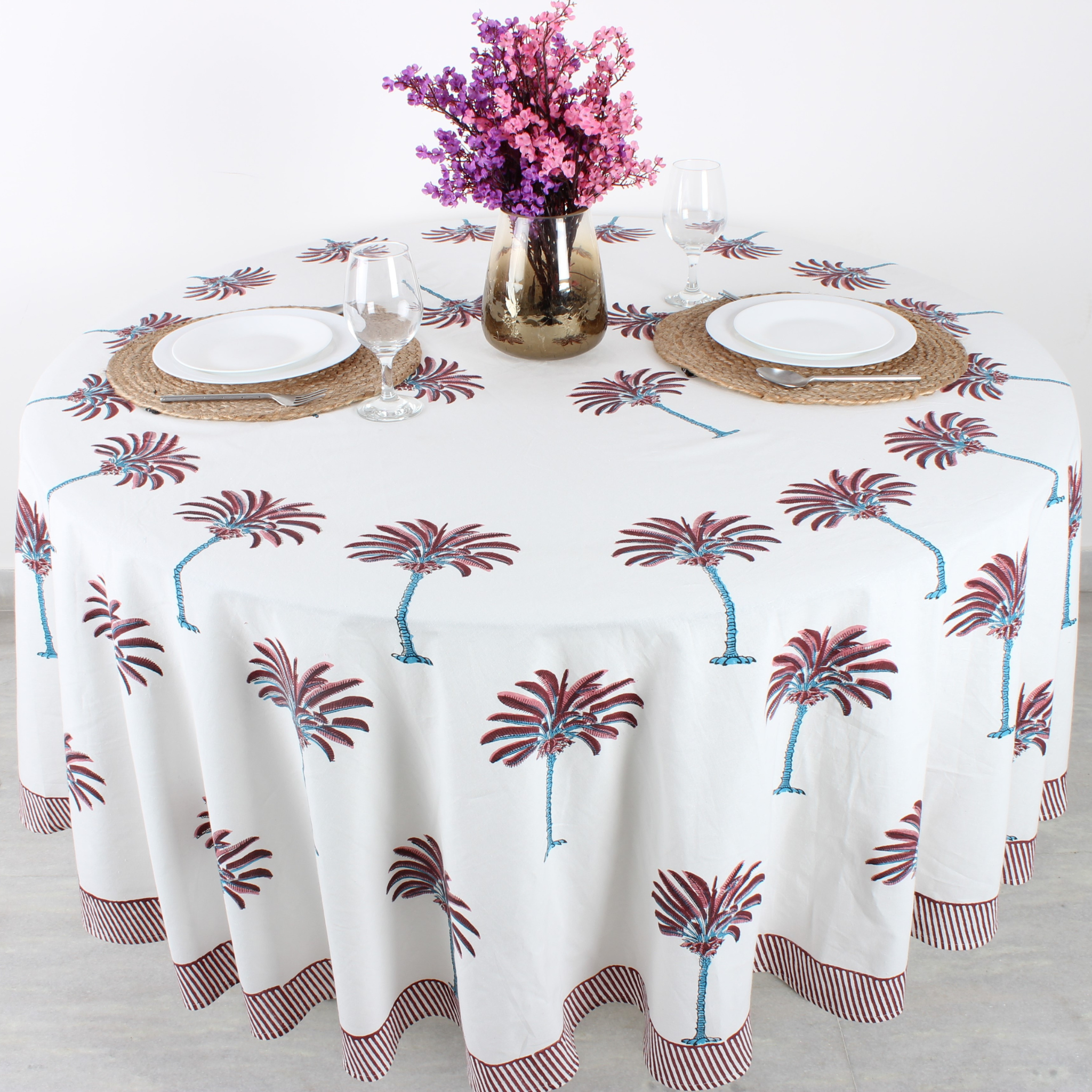 Tablecloth with palm tree design on a table set with plates, glasses, and cutlery.
