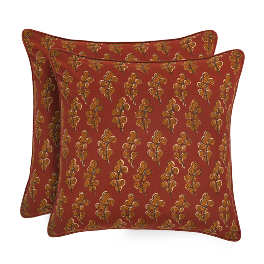 Two red pillows with gold floral patterns on a white background