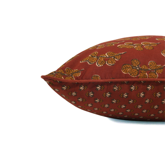 Red pillow with gold leaf pattern on a white background
