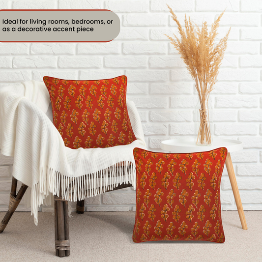 Red patterned cushions on a chair against a white brick wall.