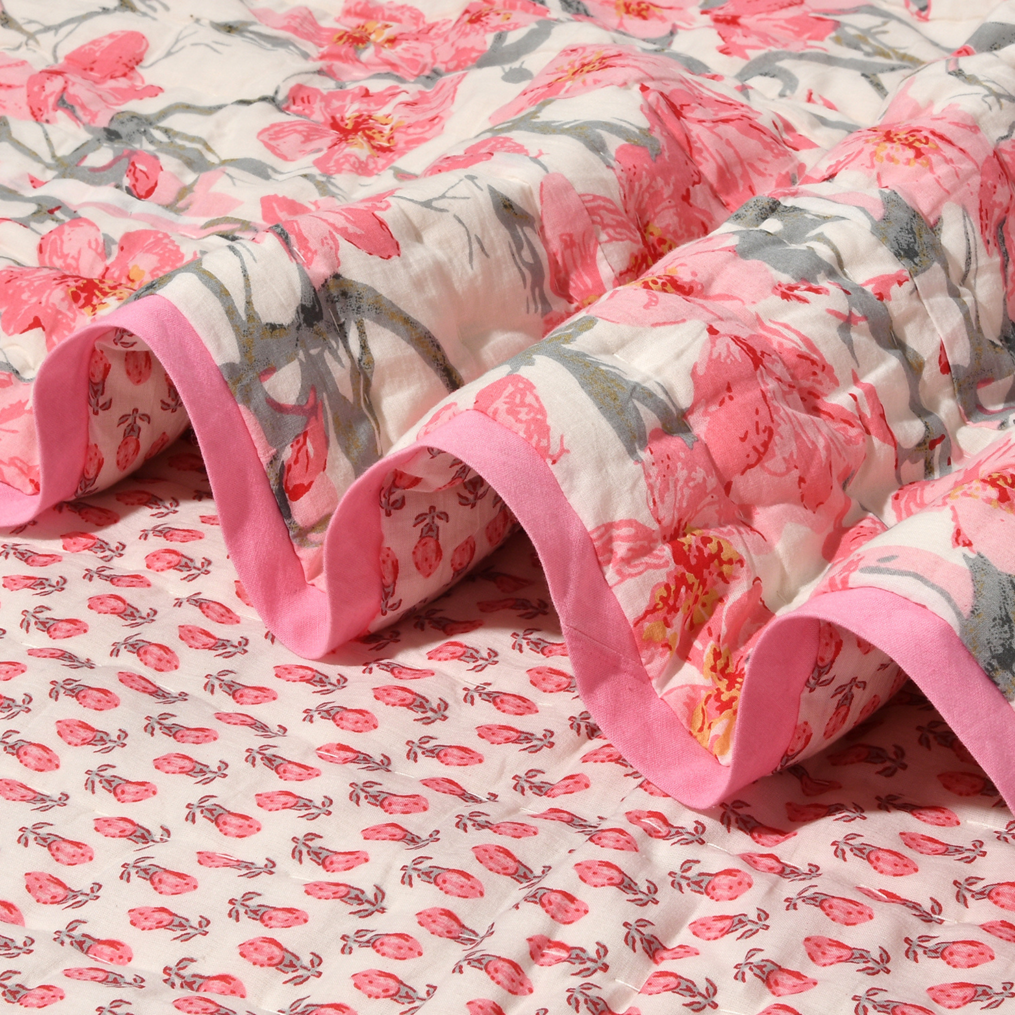 Floral quilt with pink and gray pattern on a matching fabric background