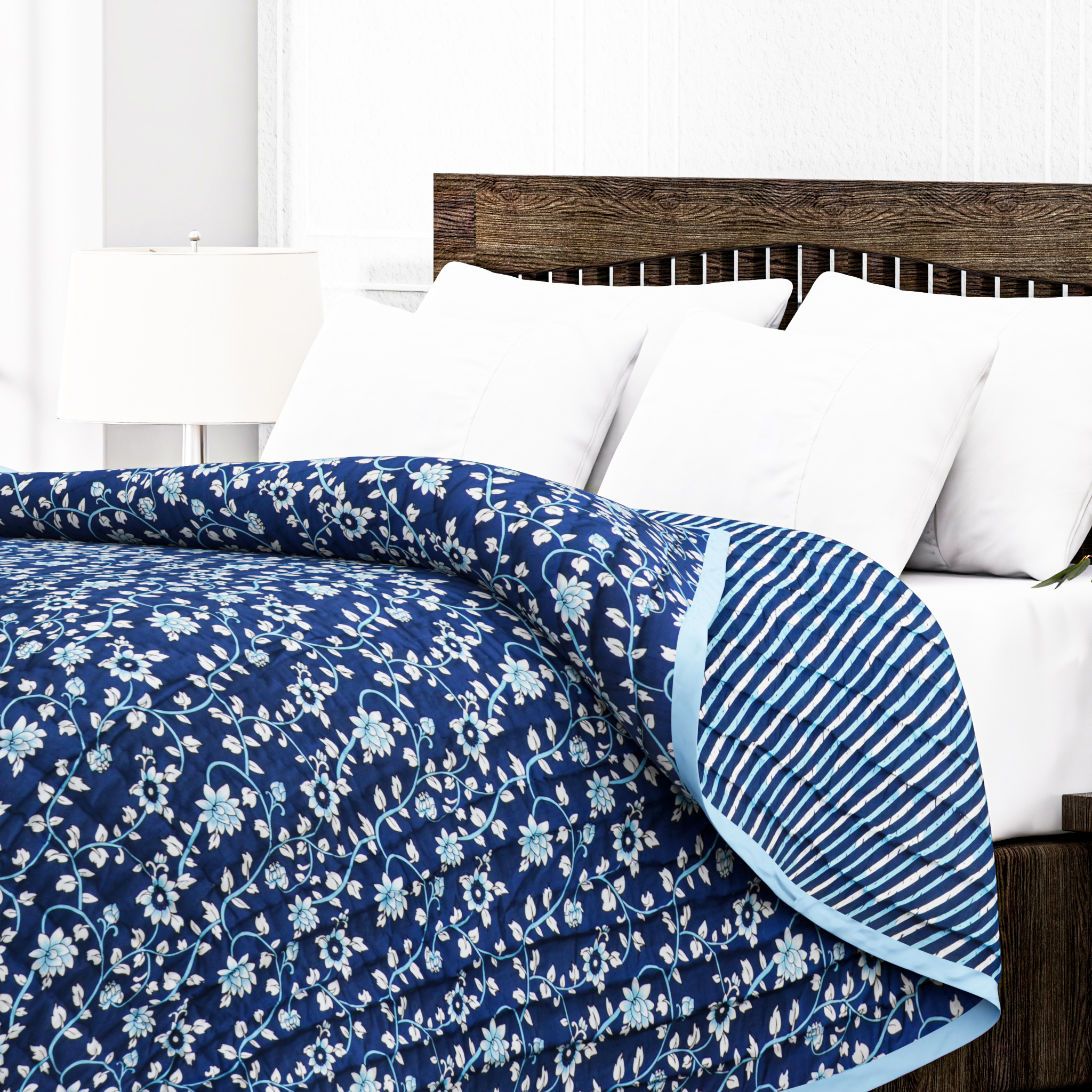 Blue floral quilt on a bed with white pillows and a wooden headboard.