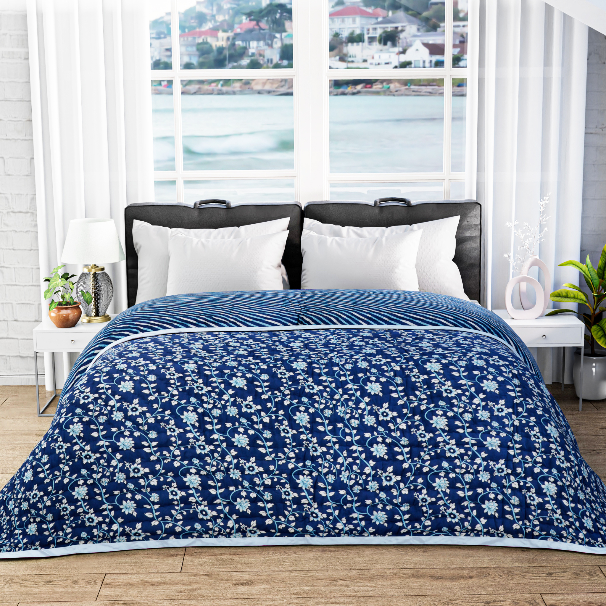 Blue floral comforter on a bed with a window view of water and buildings.