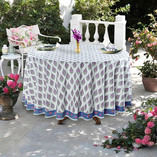 Outdoor table setting with a floral-patterned tablecloth, chairs, and decorative elements.