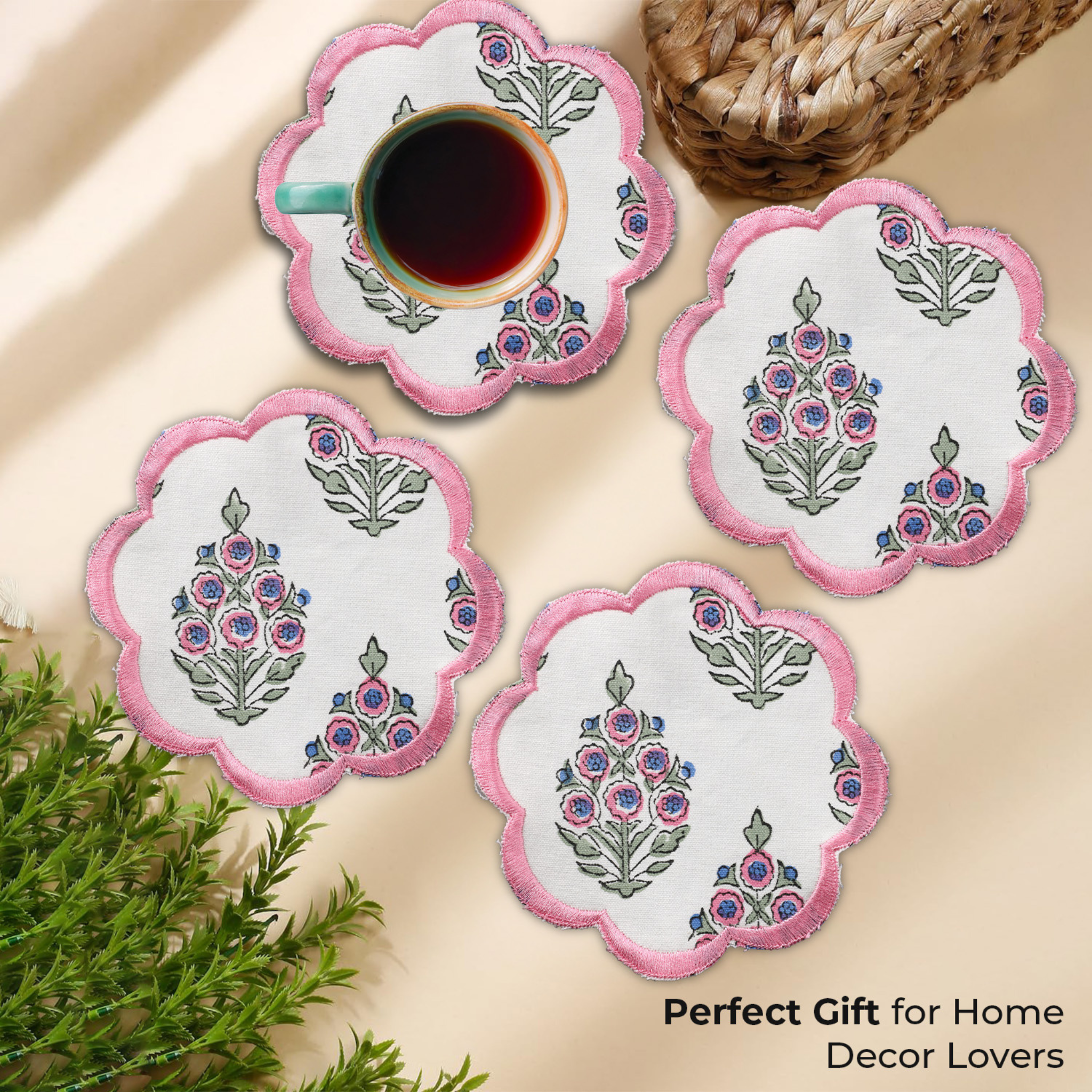 Set of floral coasters with pink trim on a beige surface, accompanied by a cup of tea.