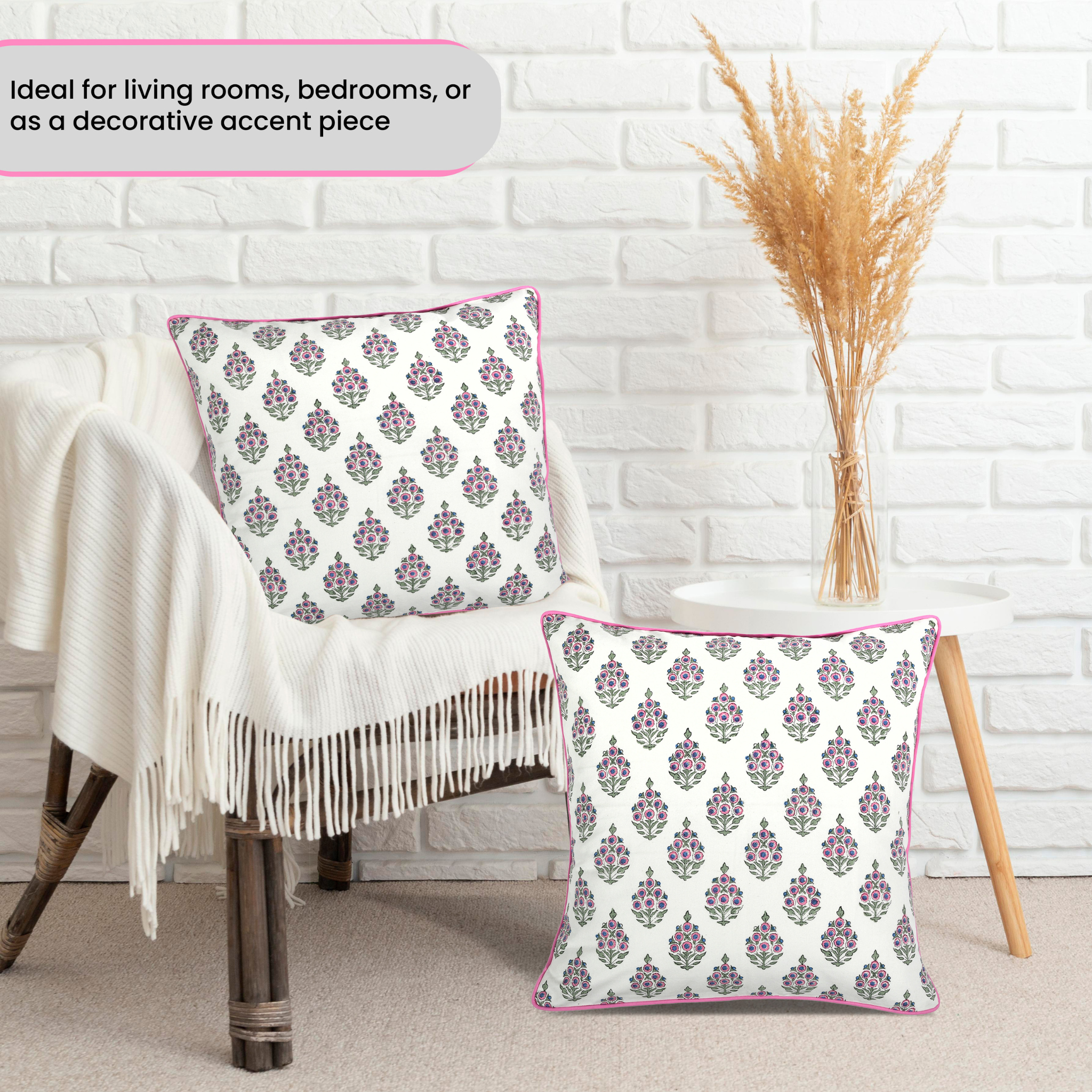 Decorative pillows with floral patterns on a chair against a white brick wall.