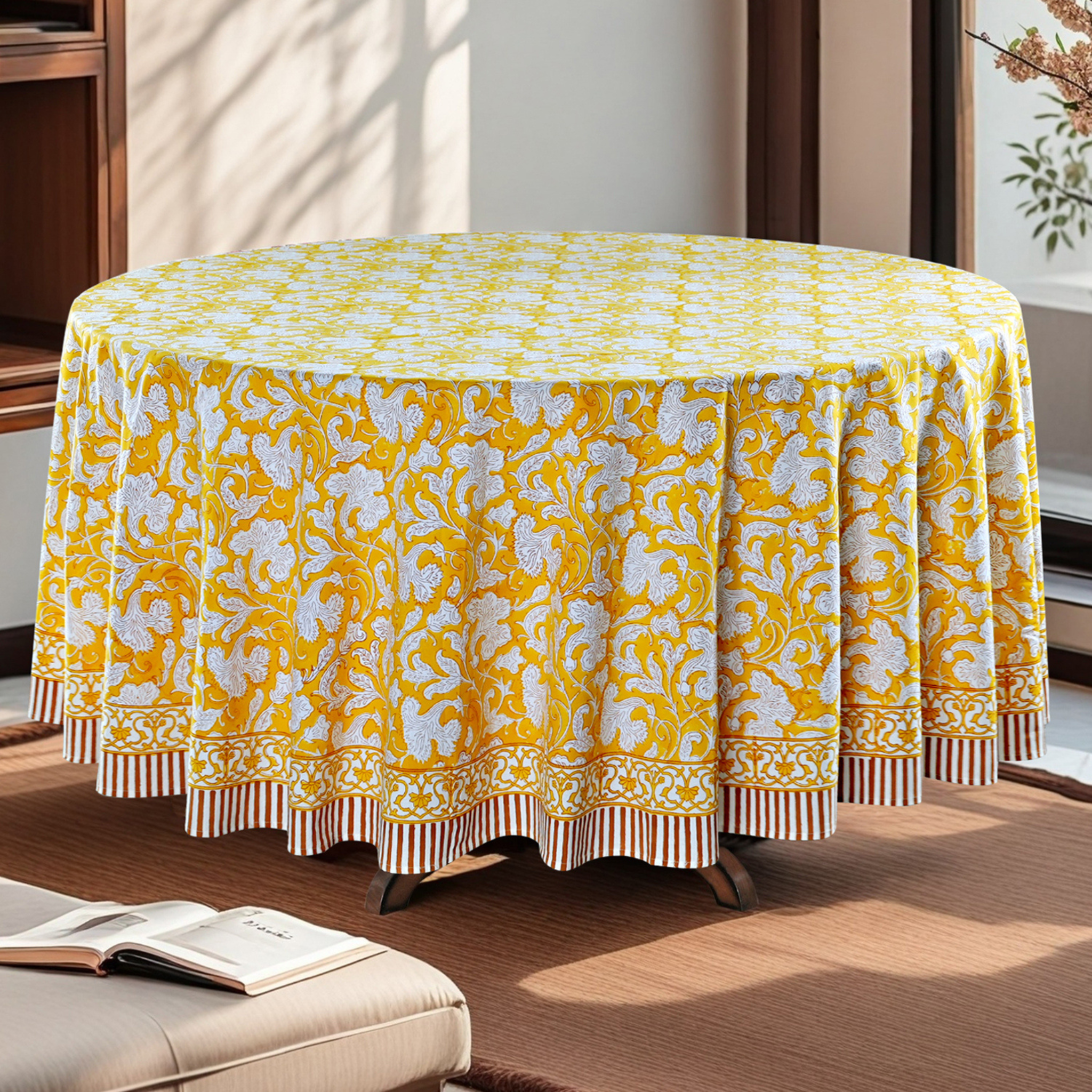 Round table with a yellow and white patterned tablecloth in a room setting.