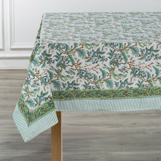 Green floral patterned tablecloth on a wooden table with a white wall background