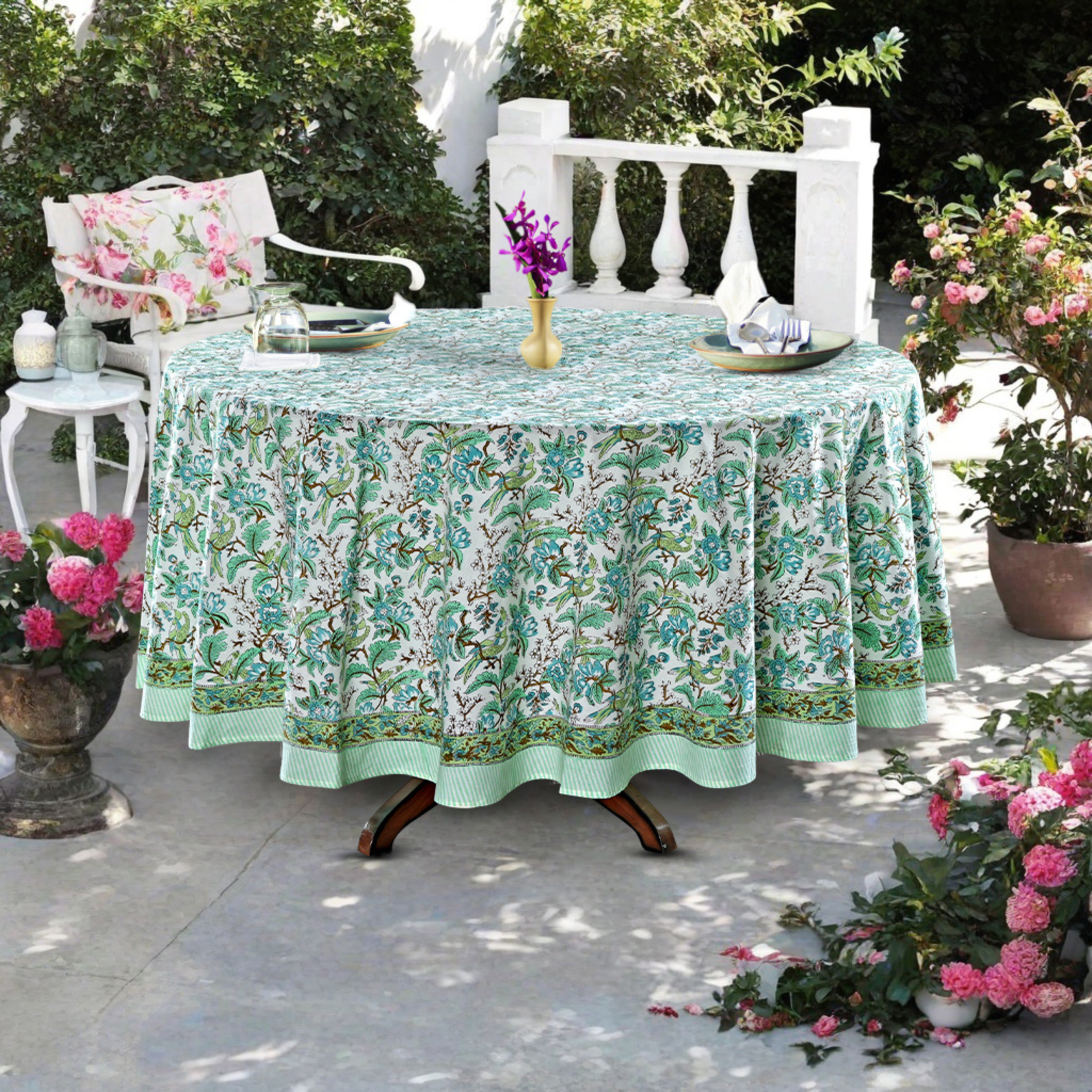 Outdoor table setting with a floral tablecloth, chairs, and potted plants.