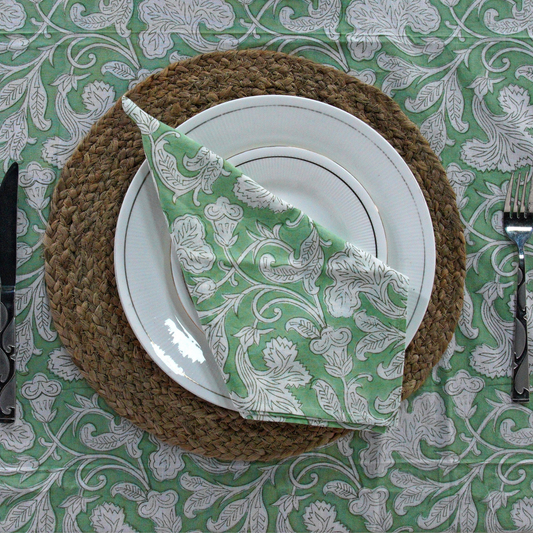 Plated dish with a green and white patterned napkin on a decorative tablecloth.