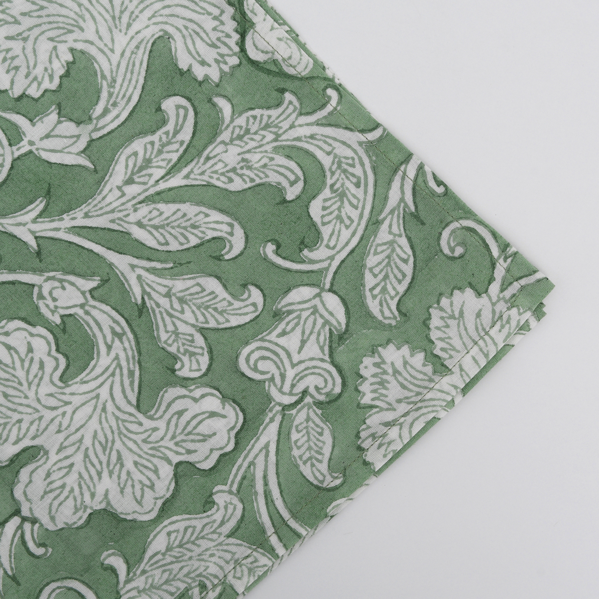 Green fabric with white floral pattern on a light gray background