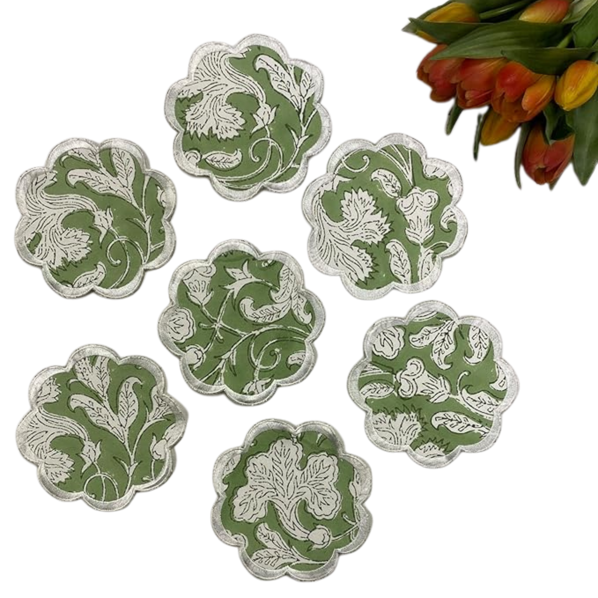 Set of six green and white floral coasters with a bouquet of tulips in the background.