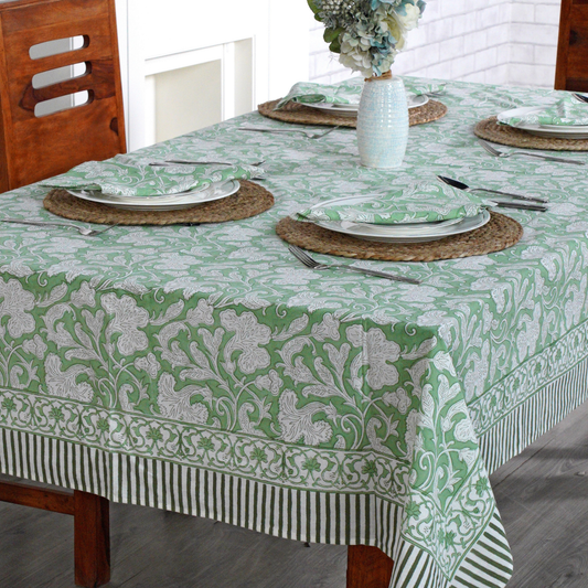 Dining table set with a green and white patterned tablecloth, plates, and cutlery.