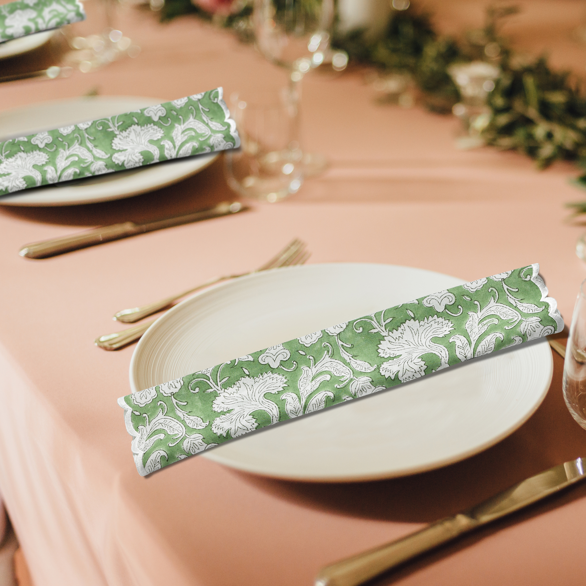 Table setting with green and white patterned napkins on a pink tablecloth.