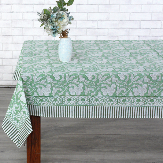 Green patterned tablecloth on a wooden table with a white brick wall background
