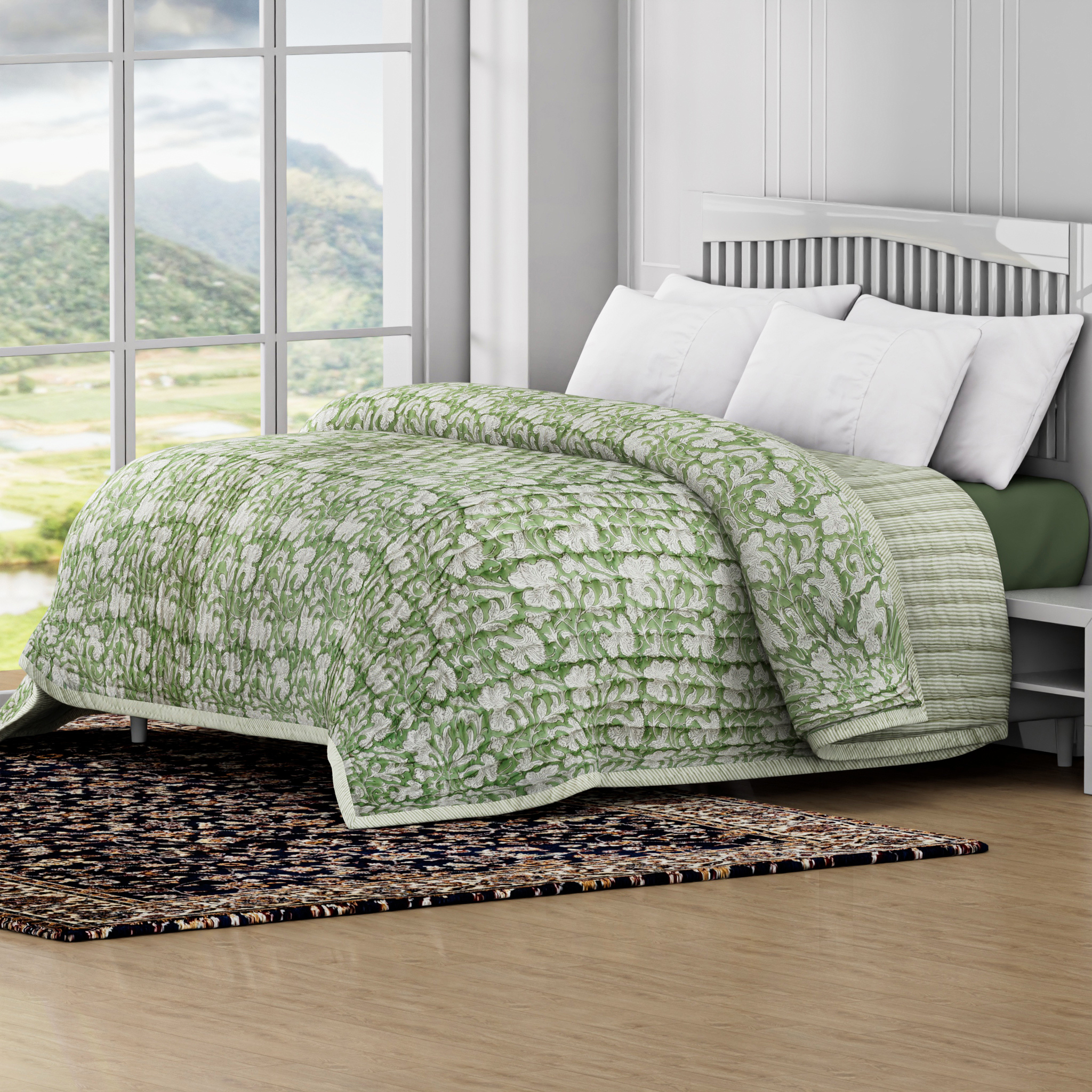 Green floral quilt on a bed in a room with large windows showing a scenic view.
