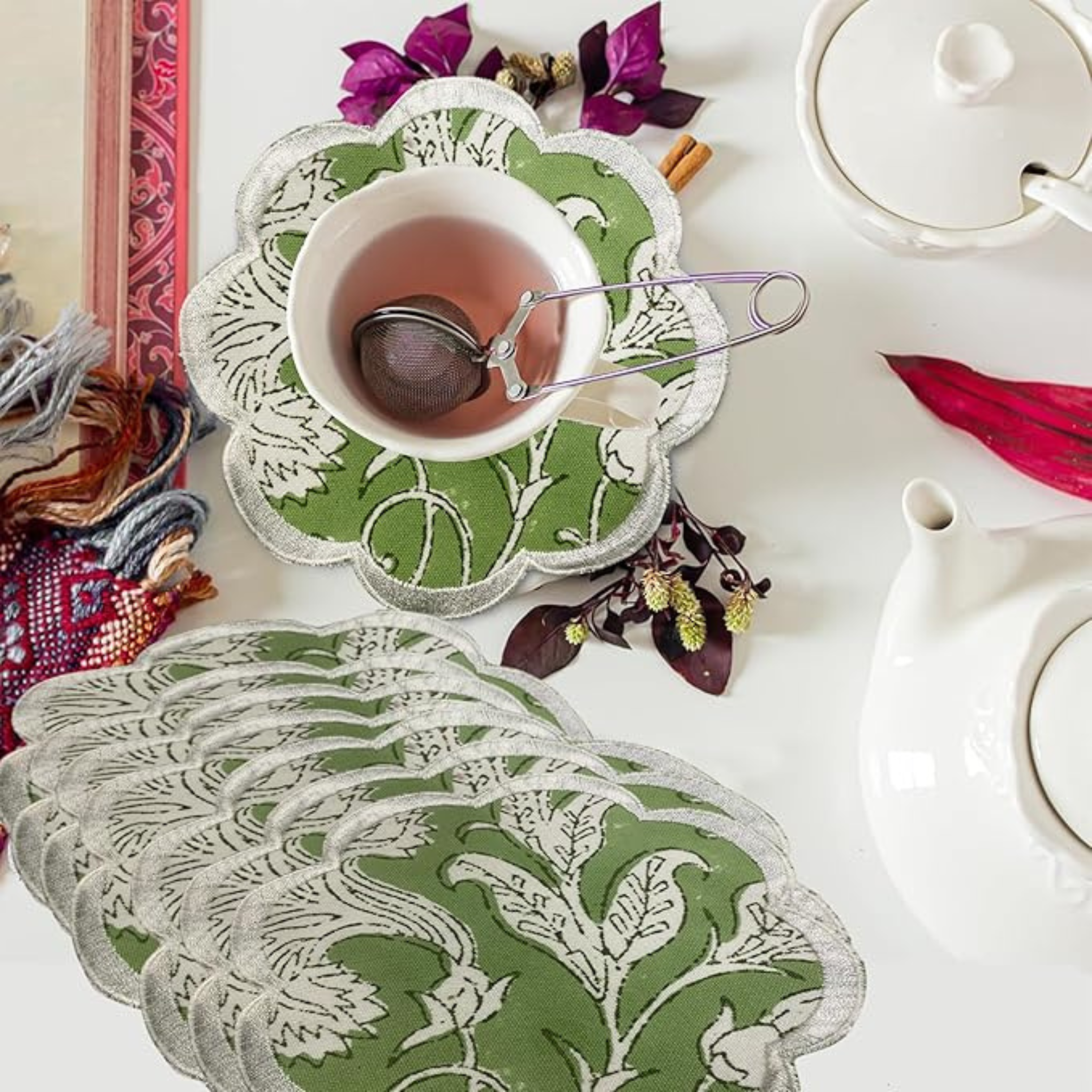 Green and white patterned coasters with a cup of tea and teapot on a decorative surface.
