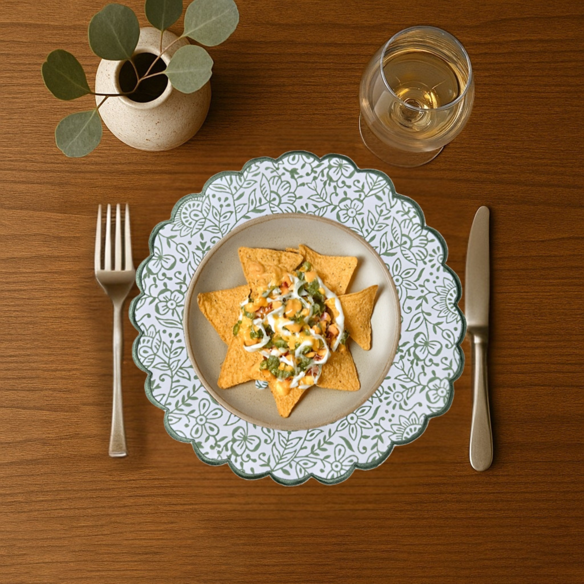 Dinner setting with a plate of food, fork, knife, and glass on a wooden table.