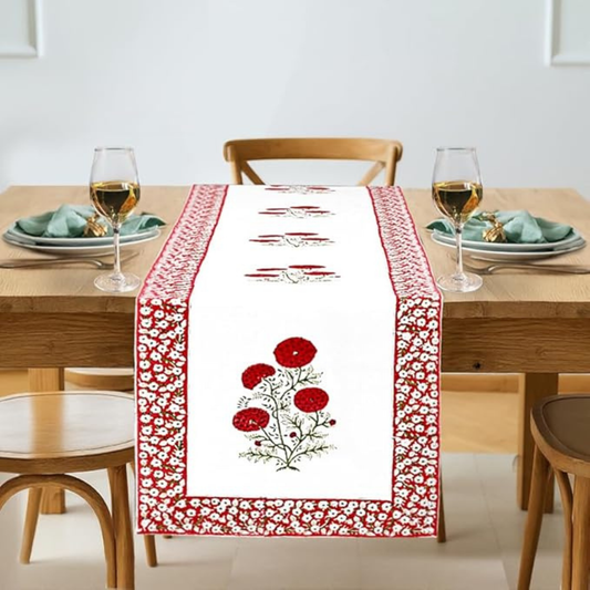 Dining table set with a decorative red and white table runner featuring floral patterns.