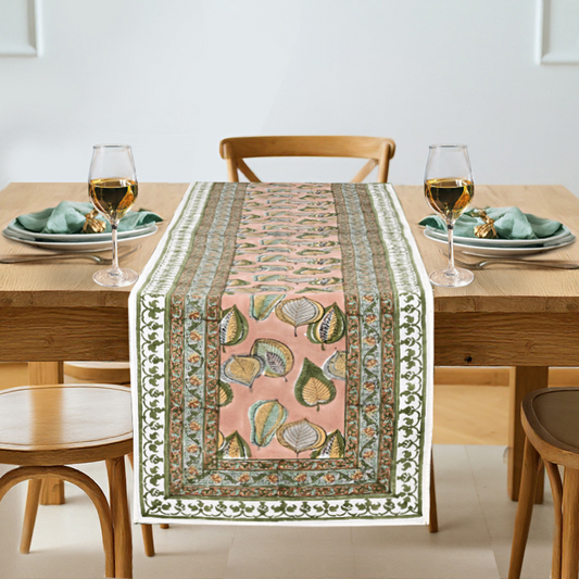 Dining table set with a decorative table runner featuring leaf patterns.
